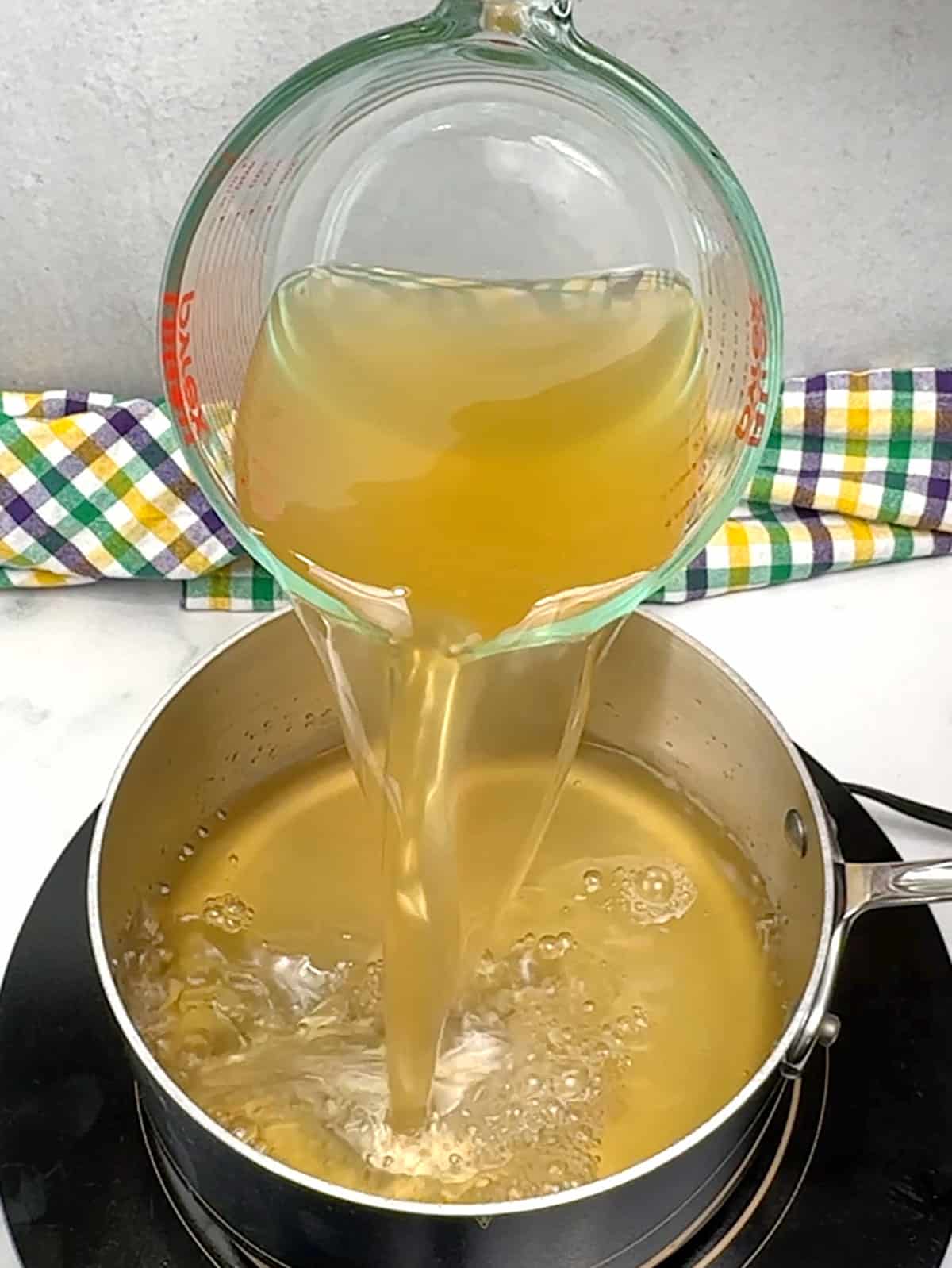 adding chicken broth to sauce pan