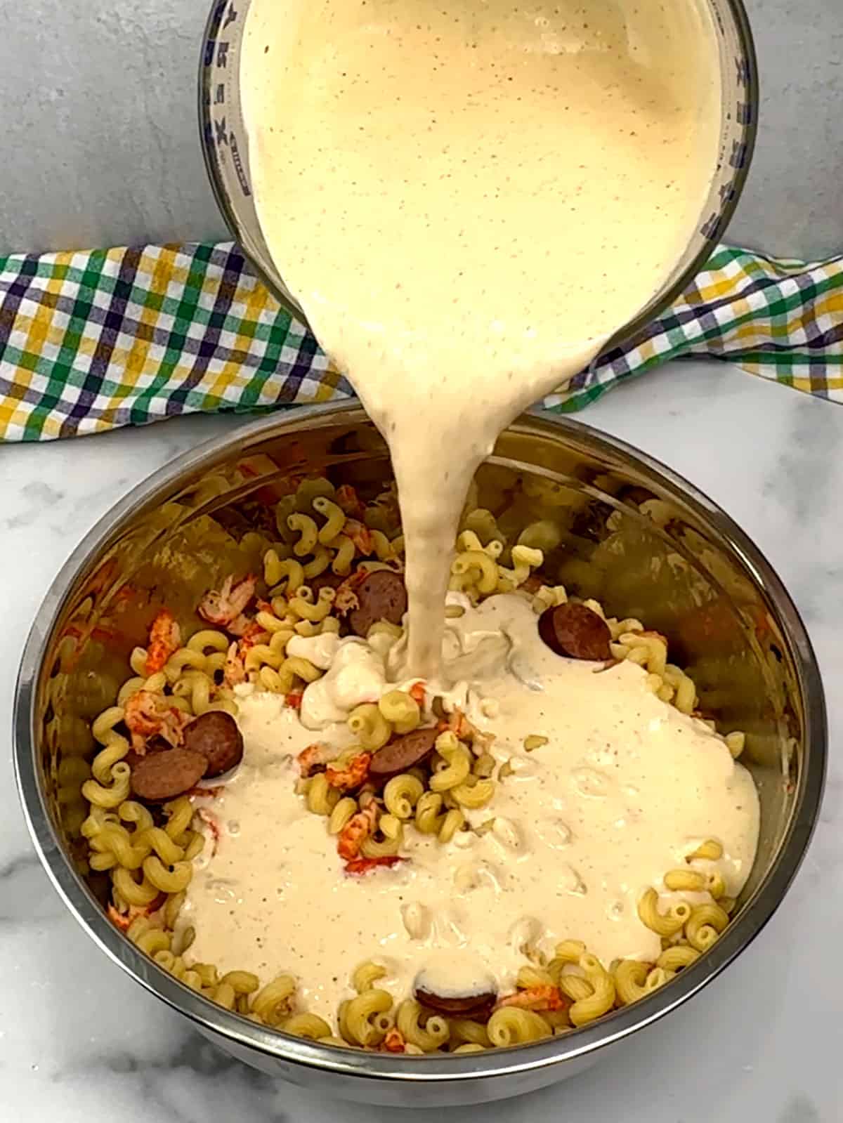 pouring sauce over pasta in bowl