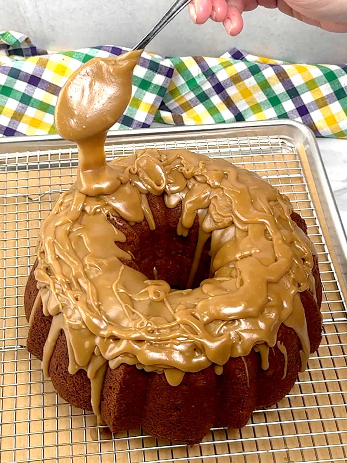 spooning praline icing over the top of the cake
