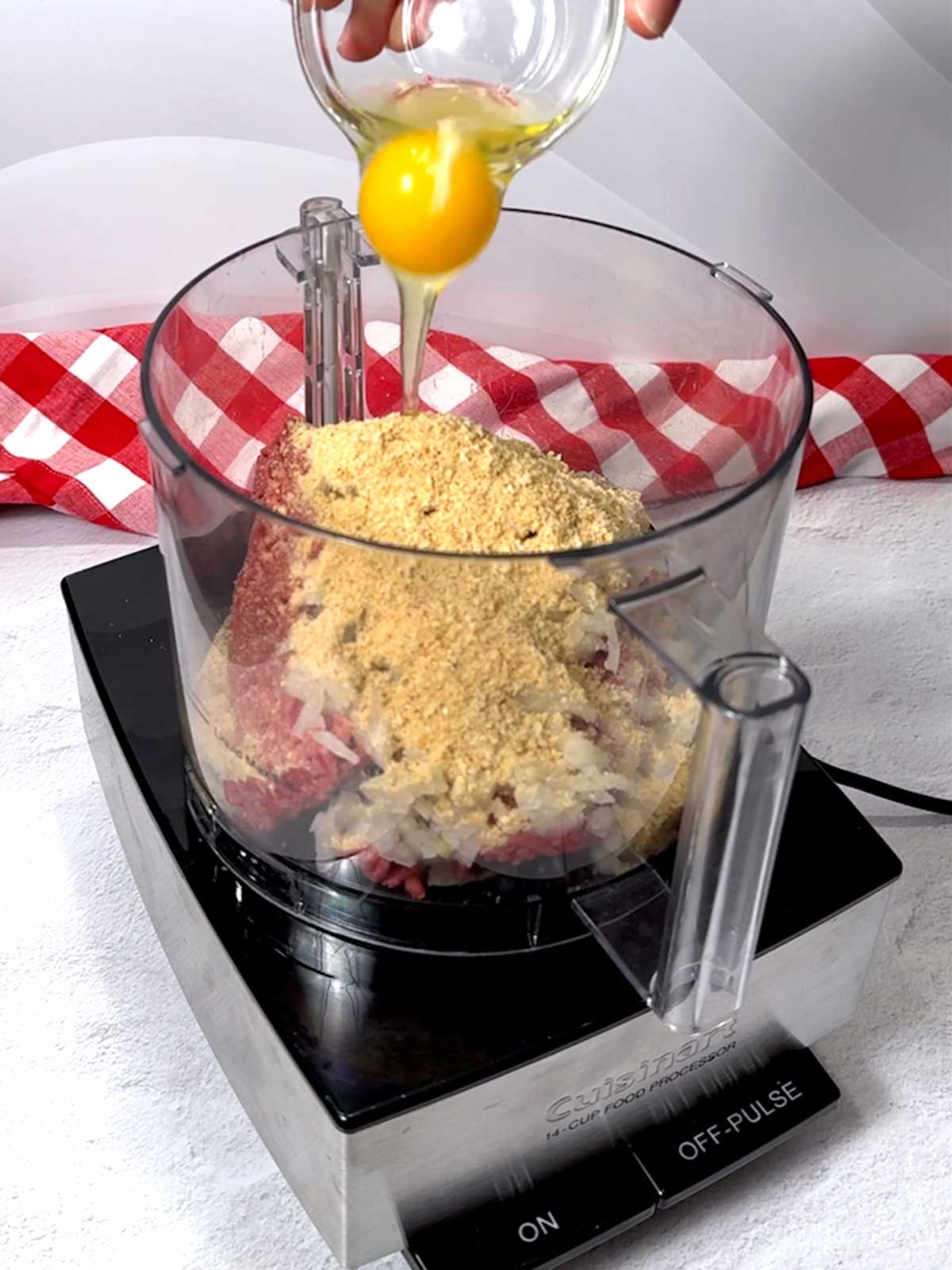 Adding an egg to the food processor with the Salisbury steak ingredients.