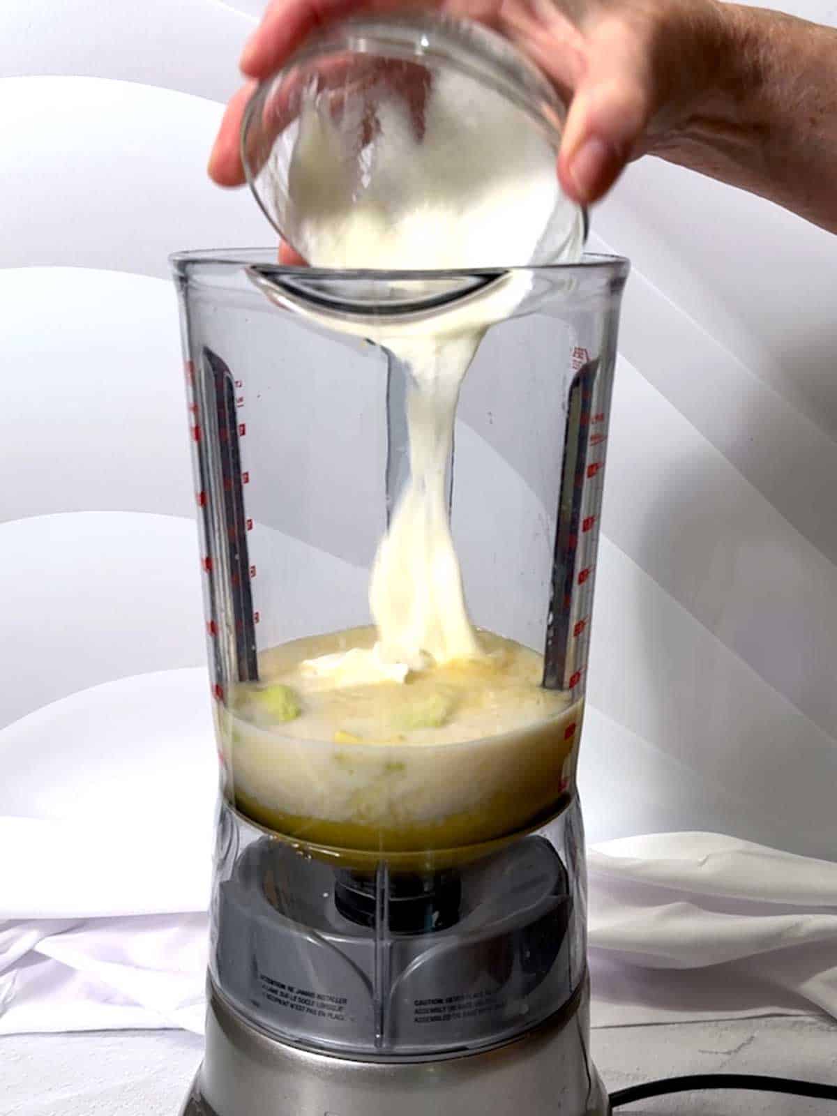 Adding Greek yogurt to the blender.