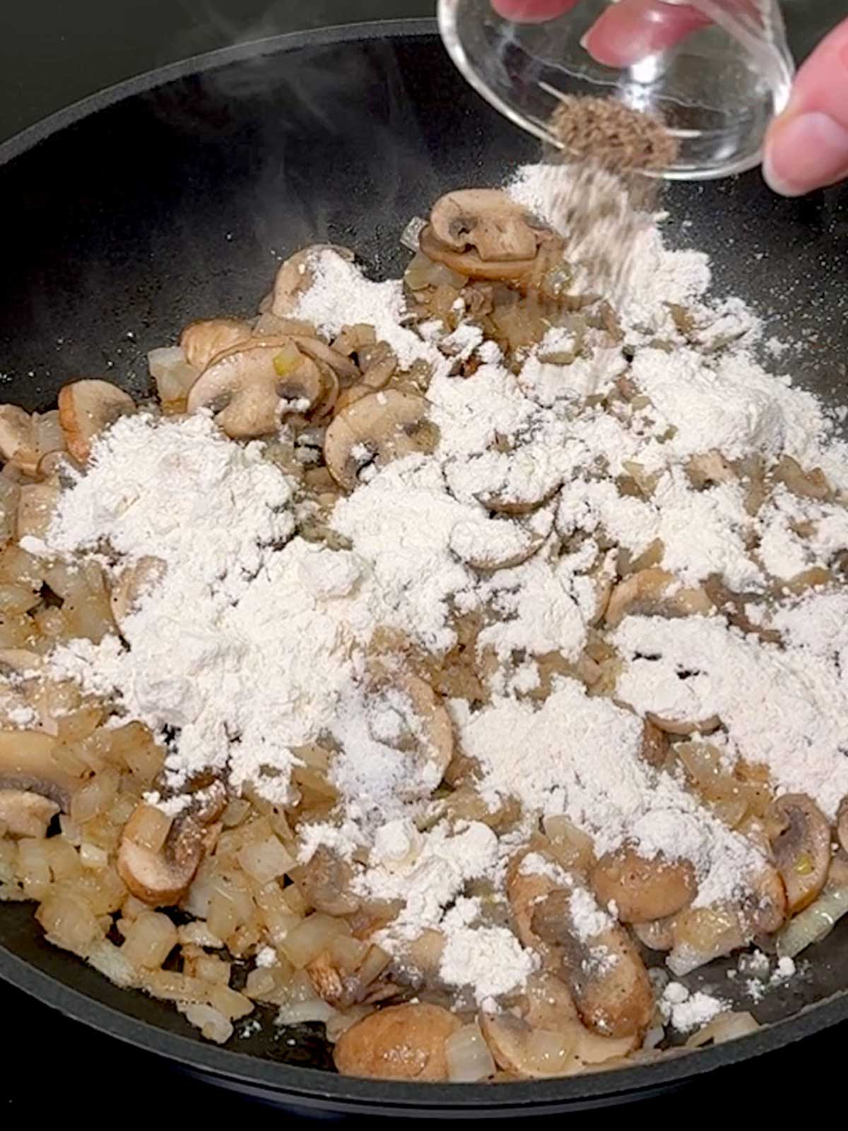 Adding pepper to the pan.
