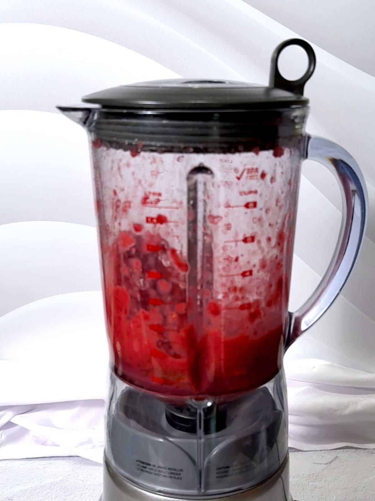 Processing raspberries with orange juice, honey and crushed ice in a blender.