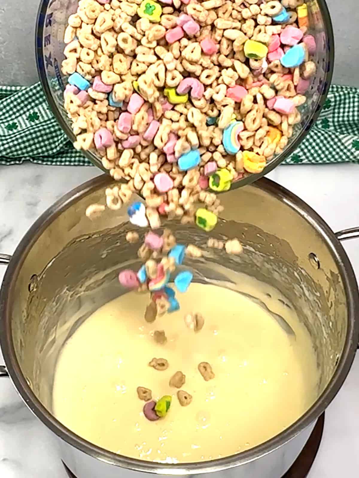 adding Lucky Charms cereal to malted marshmallow mixture