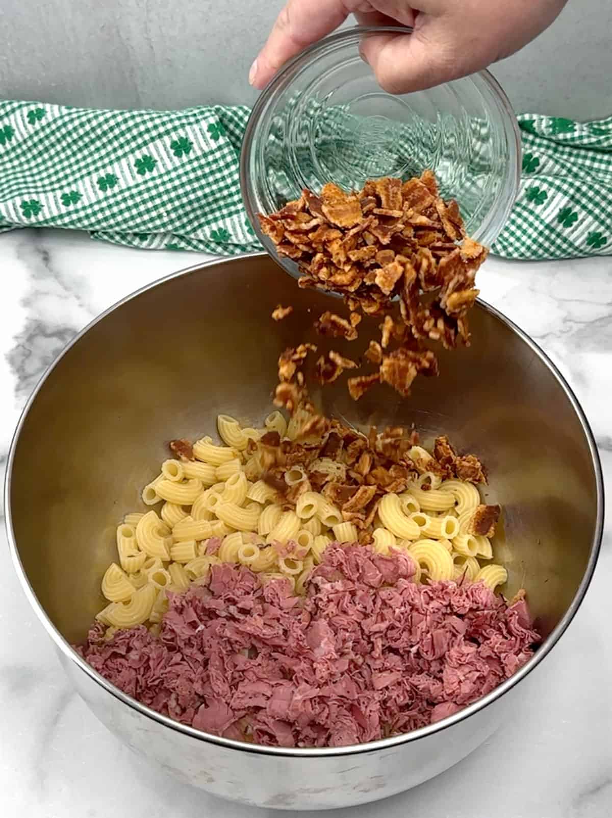 adding pasta, pastrami, and bacon to large bowl