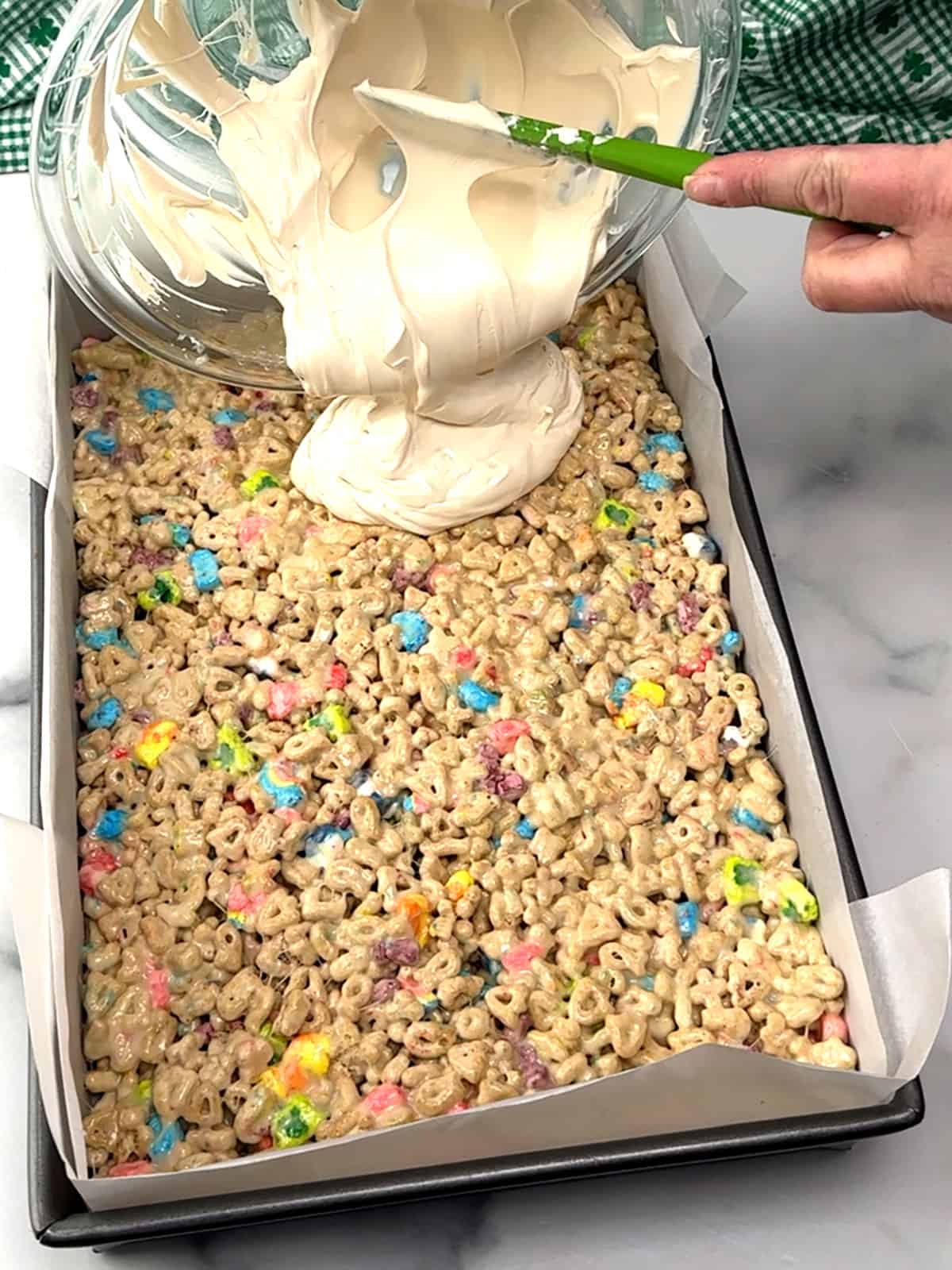 pouring white candy melts on top of marshmallow treats