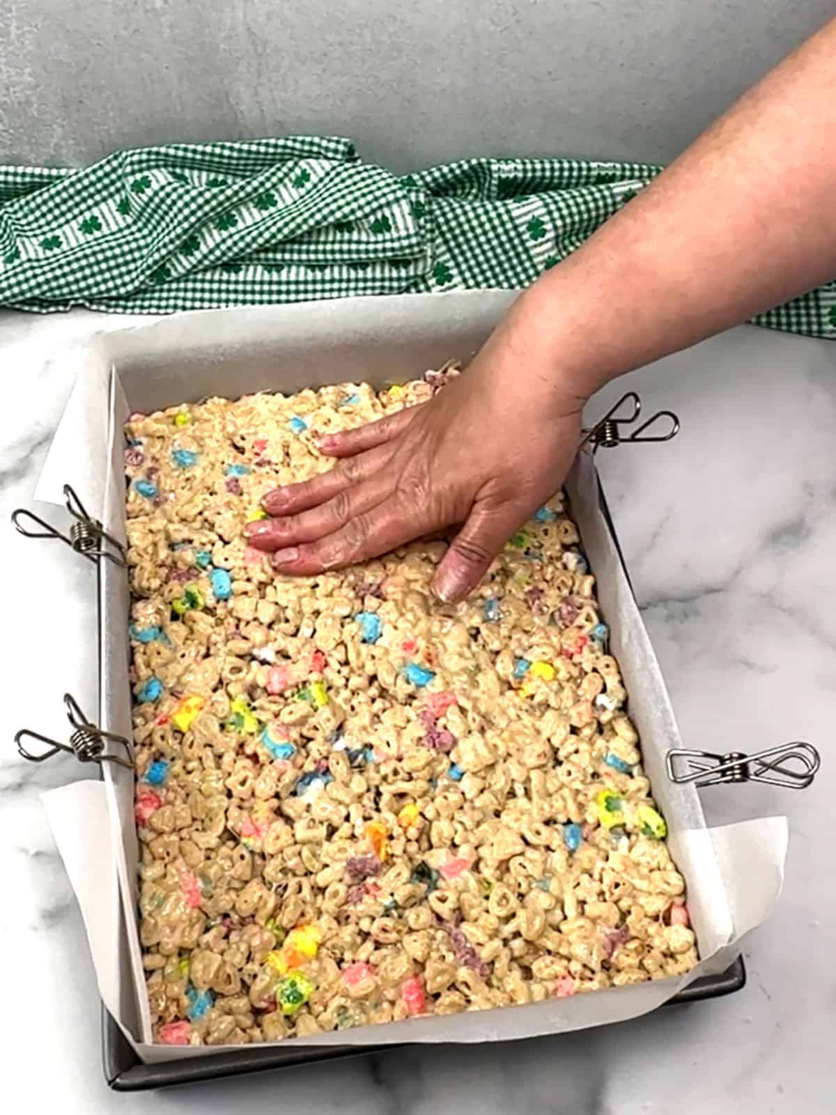 pressing Lucky Charms Marshmallow treats into pan