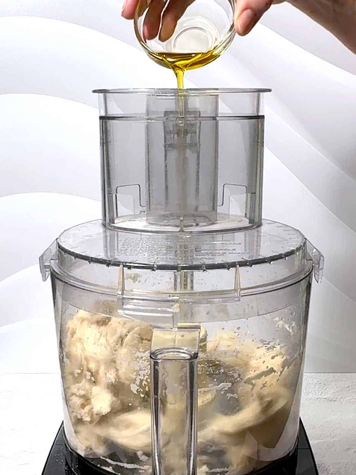 Adding olive oil to the food processor while it was running.