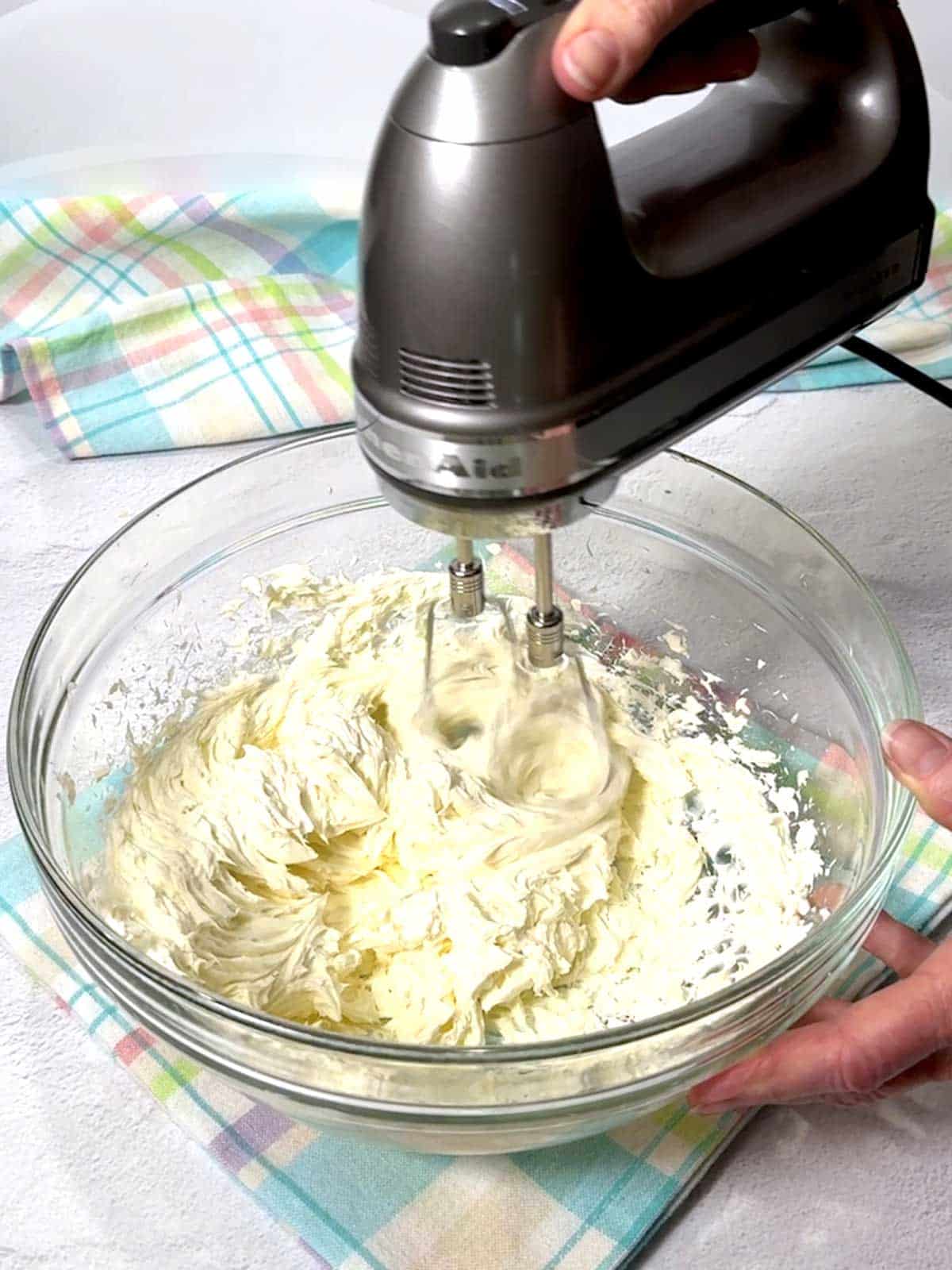 Beating cream cheese with electric mixer.