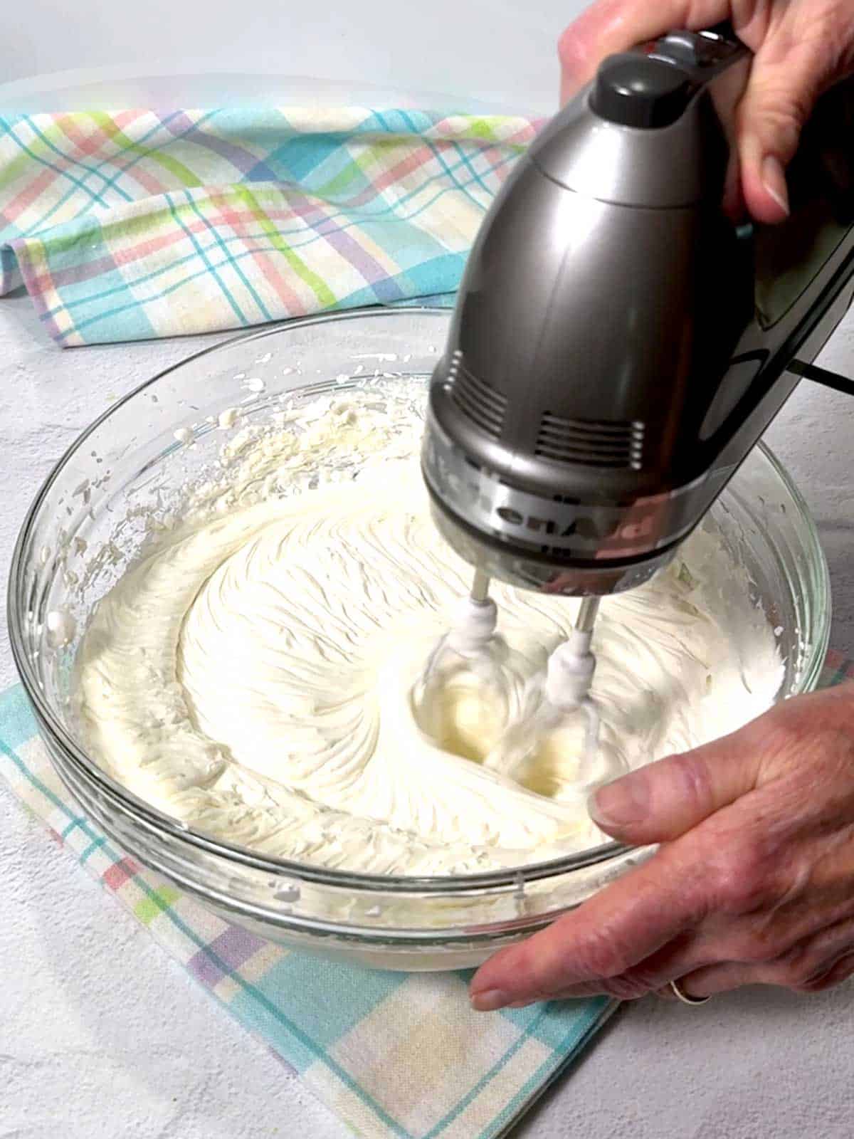 Beating cheesecake mixture with electric mixer.