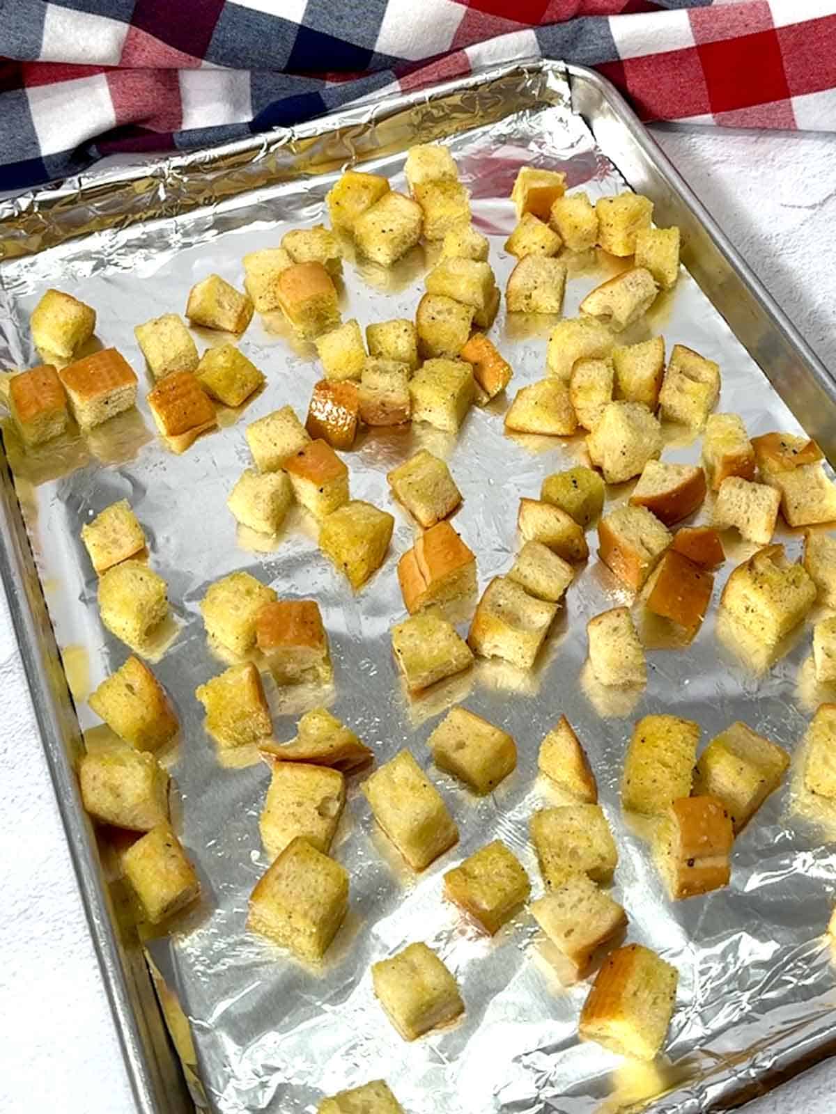 Croutons on aluminum foil lined half-sheet pan ready for the oven.