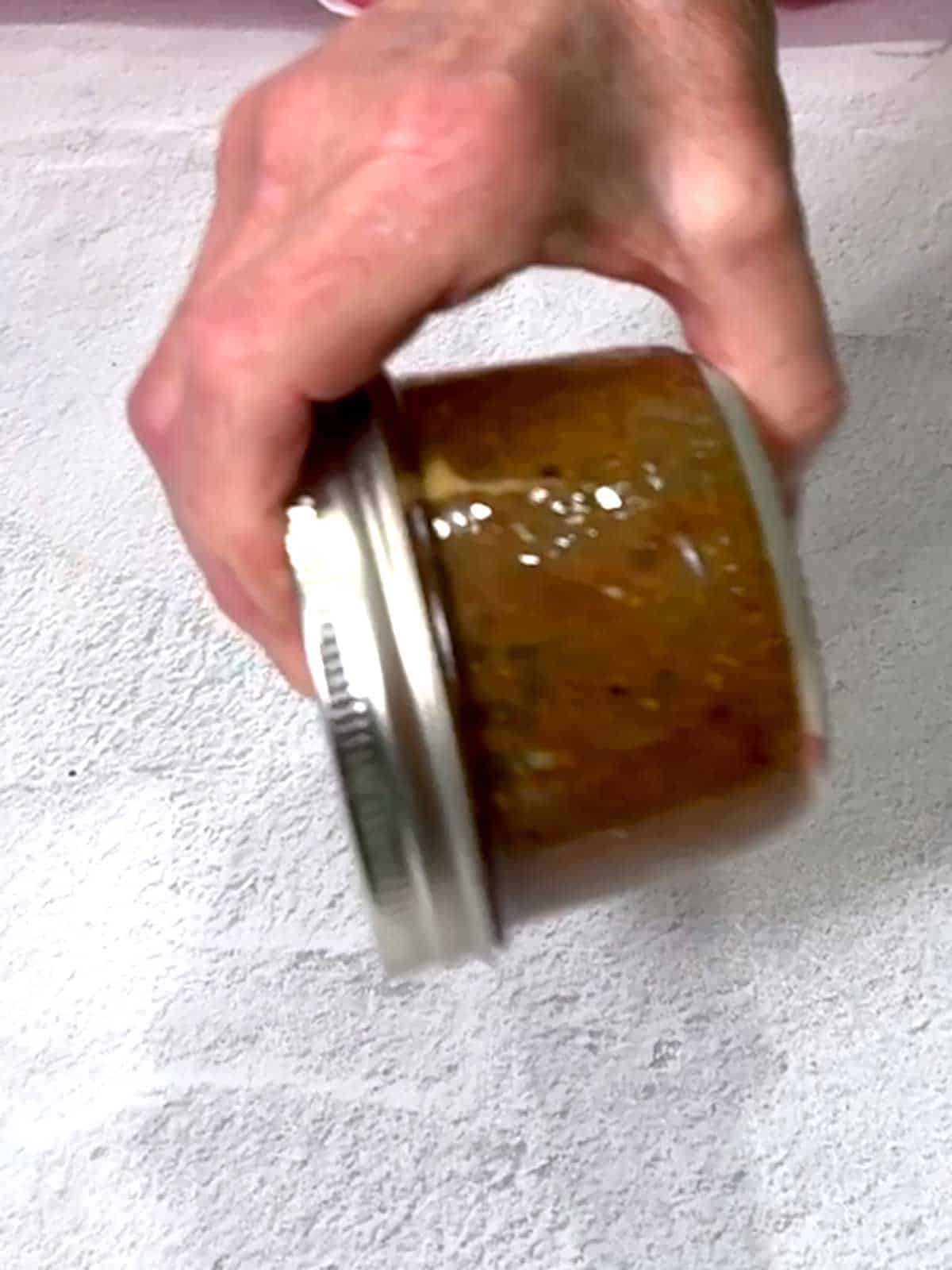Shaking the jar with the marinade to combine all ingredients.