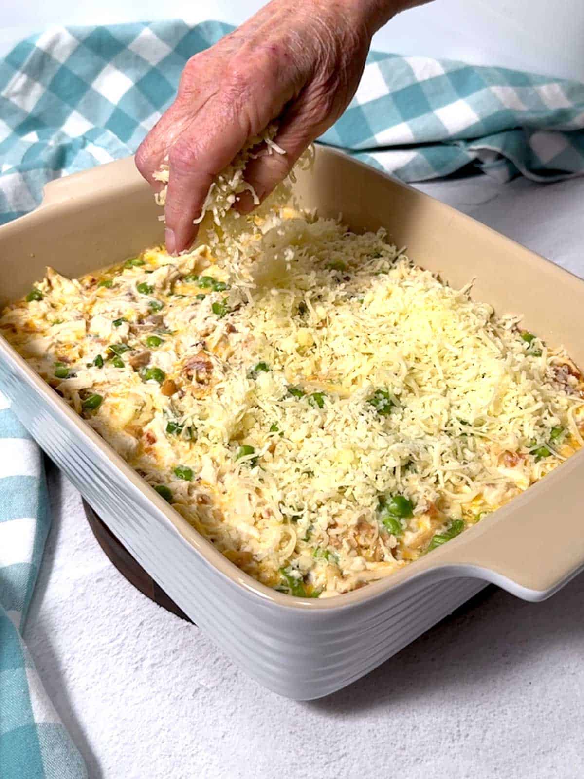 Sprinkling shredded Monterey Jack cheese on the top of the partially baked casserole.