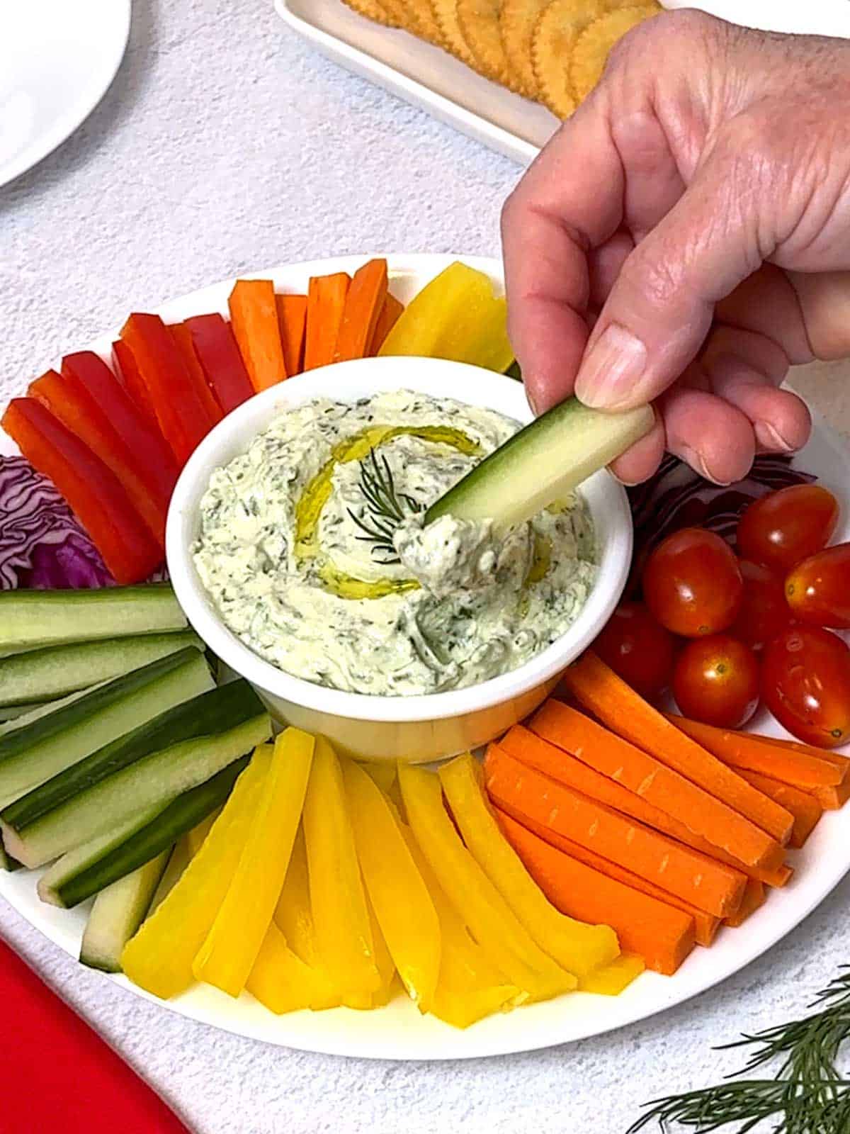 Dipping a cucumber strip into the green goddess dip.