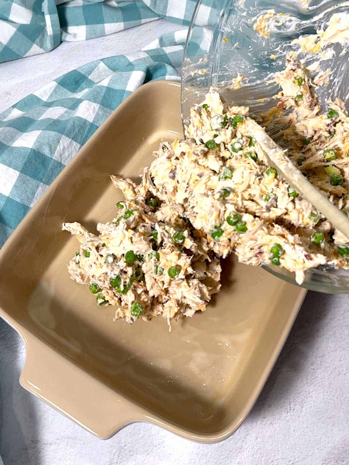 Transferring chicken mixture to a casserole dish.