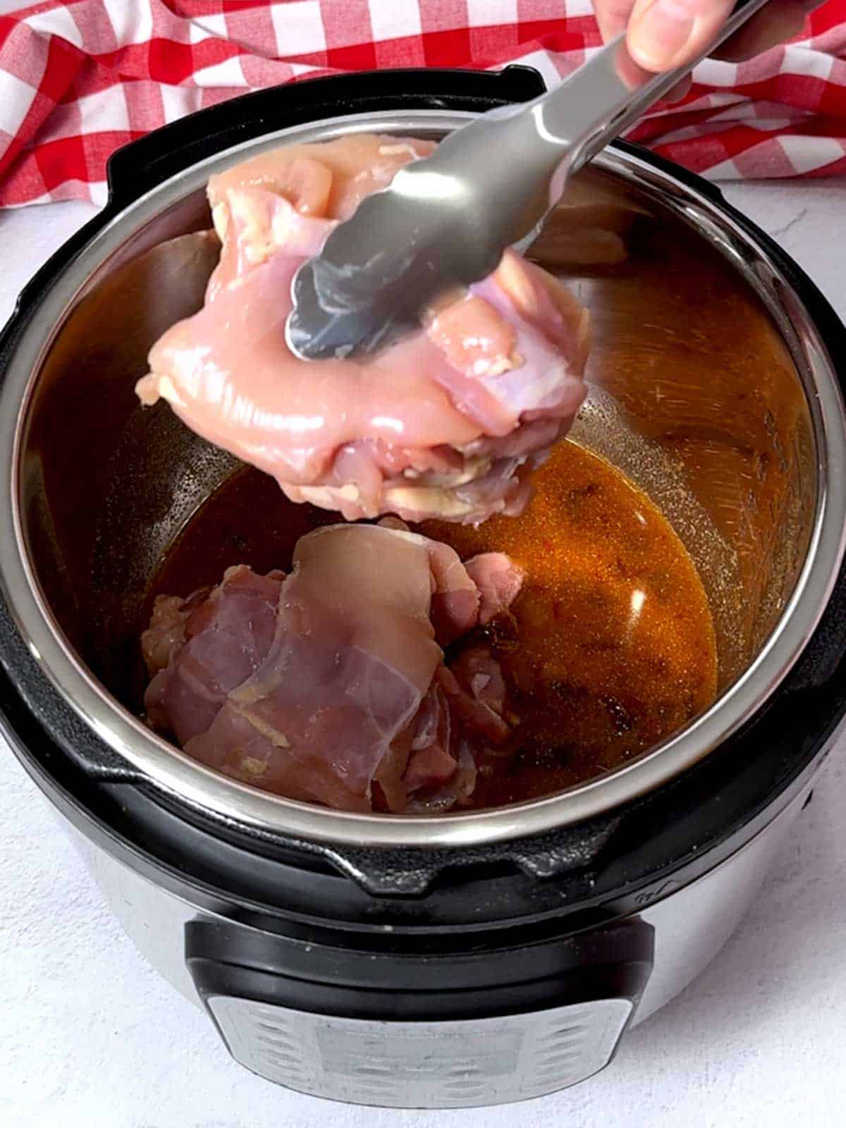Adding chicken thigns to the Instant pot.