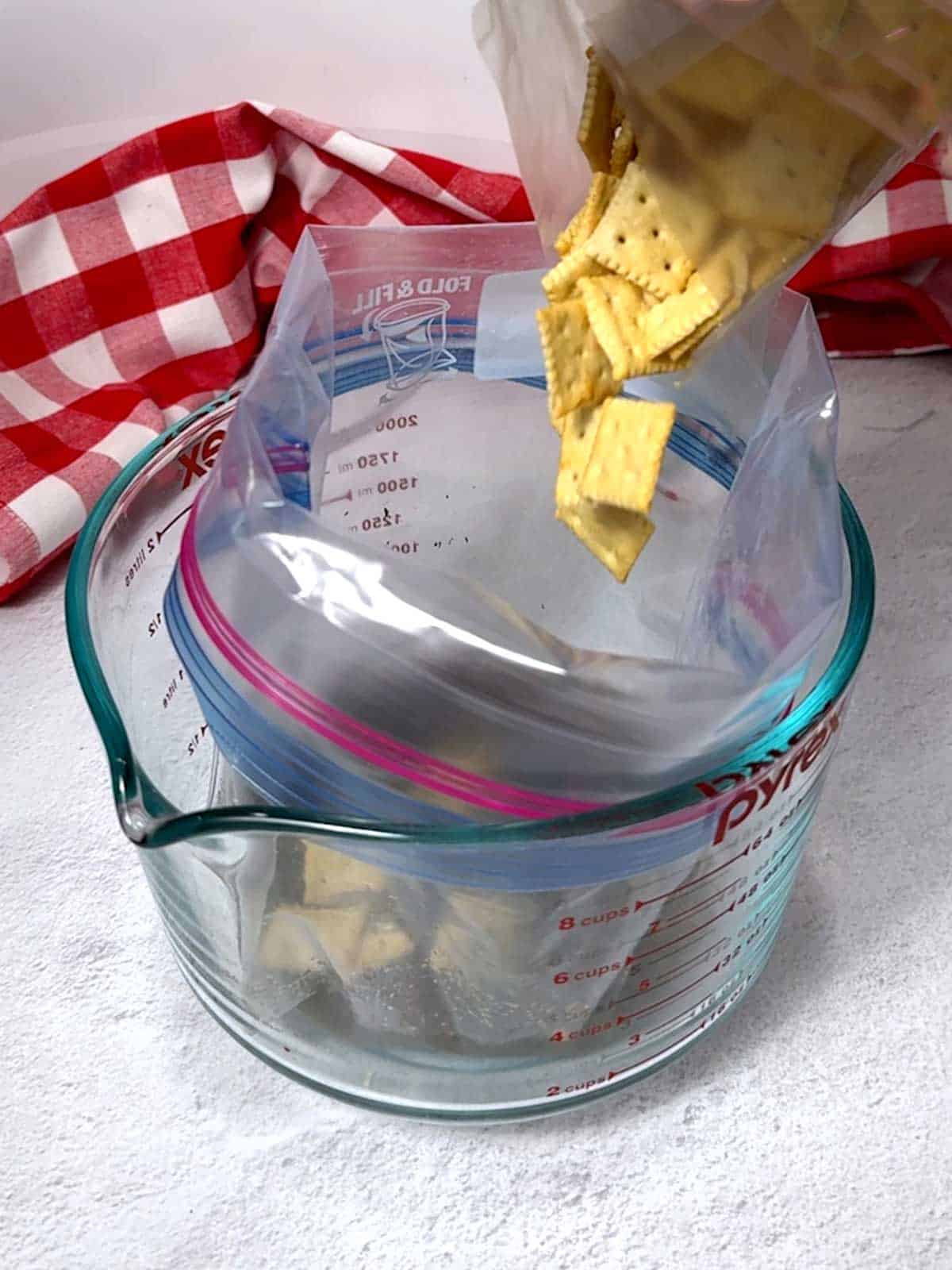 Adding mini saltines to the Ziploc bag.