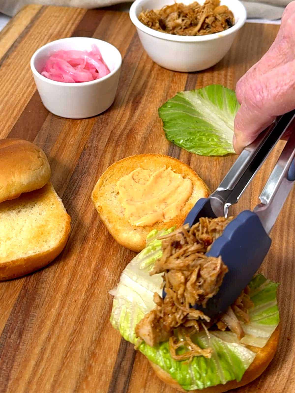 Adding the shredded chicken to the slider bun.