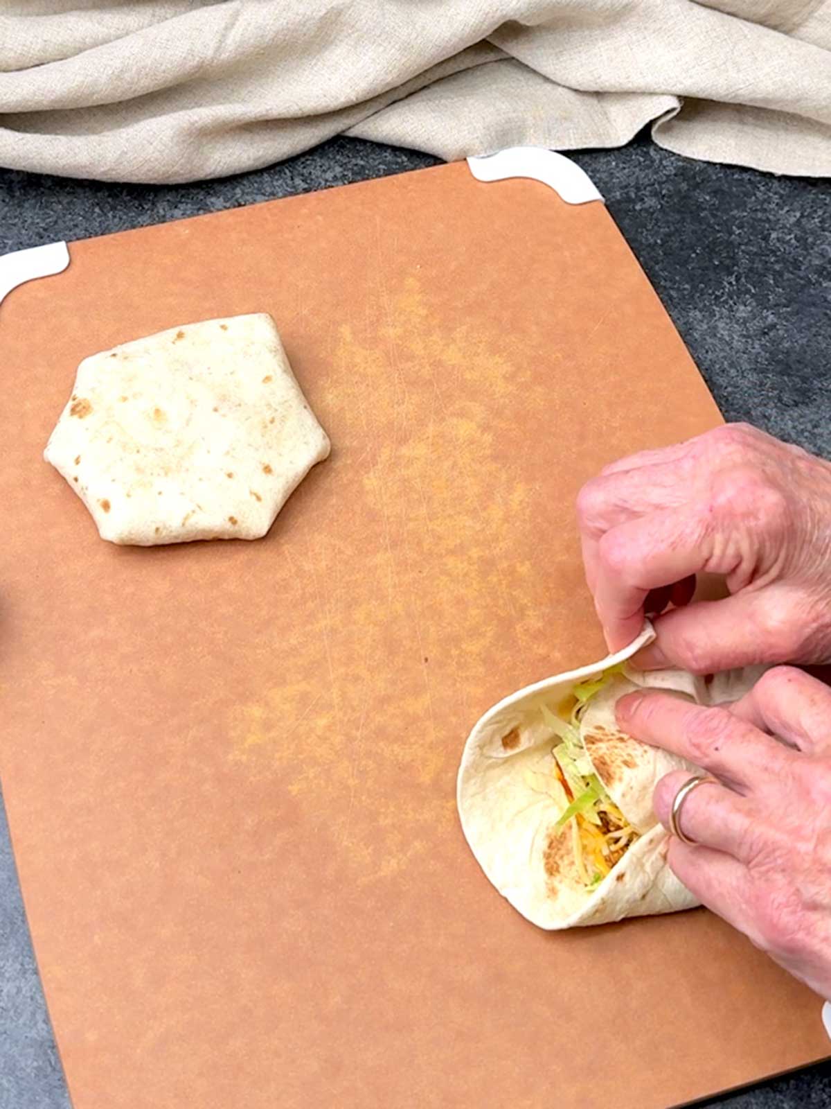 Folding and pleating the larger tortilla over the filling.
