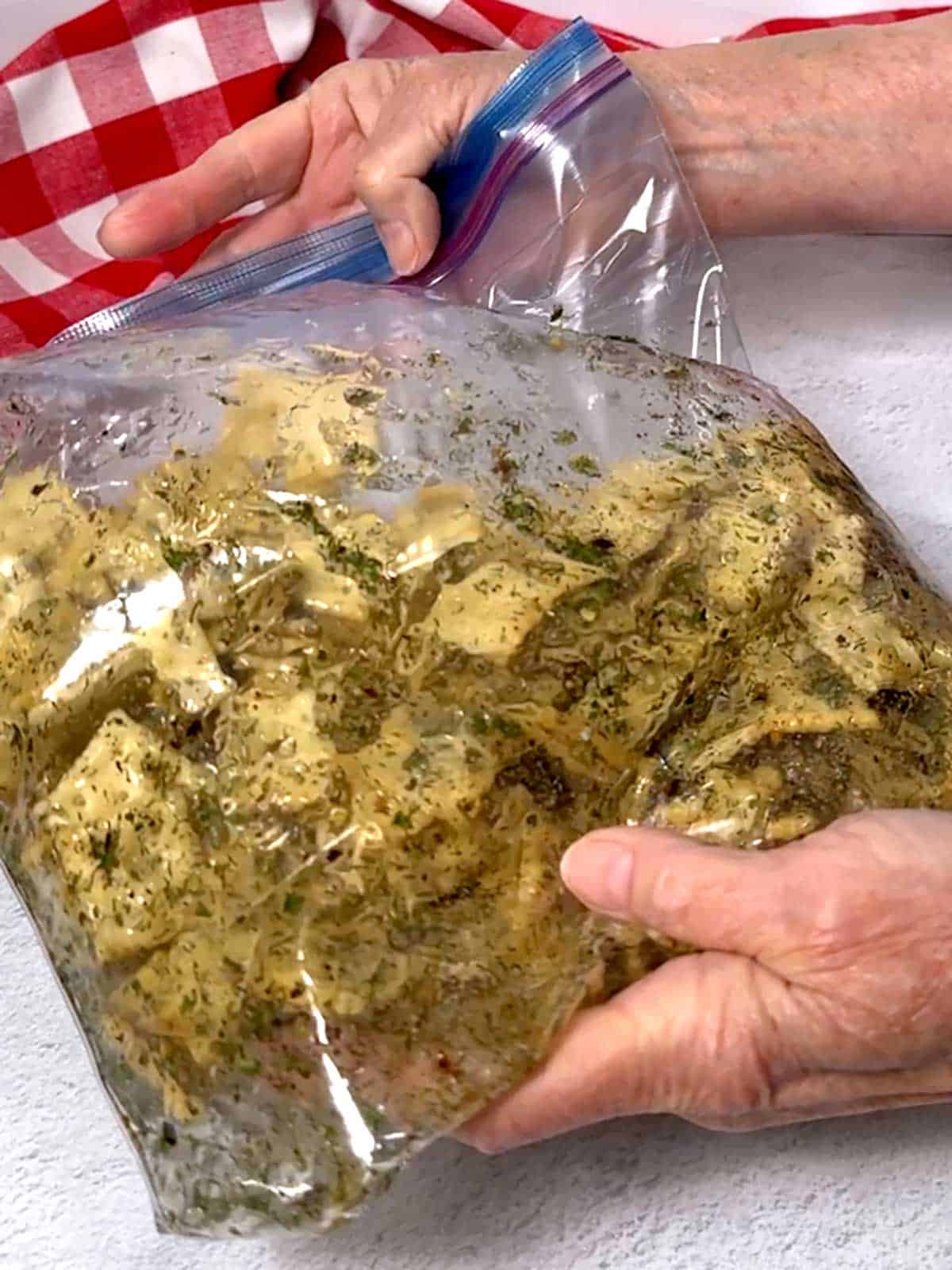 Shaking the mini saltines in the seasoned oil in the Ziploc bag.