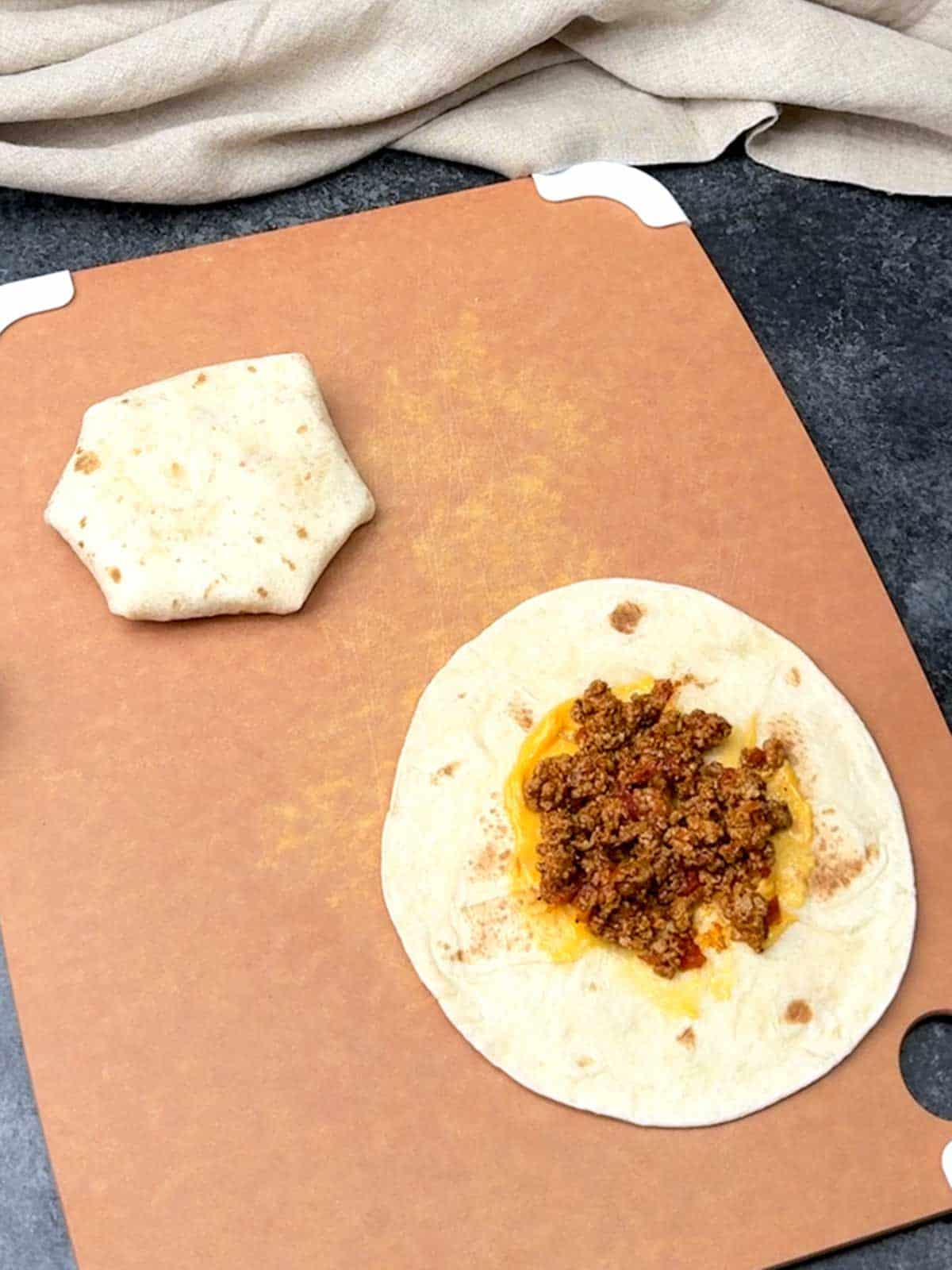 Adding taco meat on top of the salsa con queso.