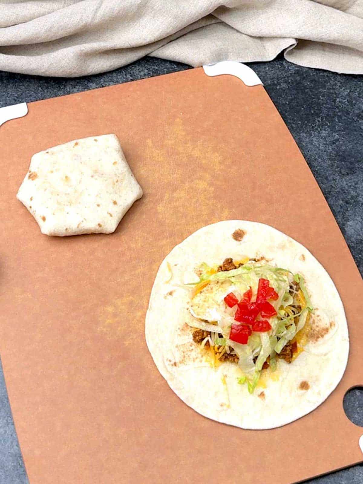 Adding tomatoes to the crunchwrap.