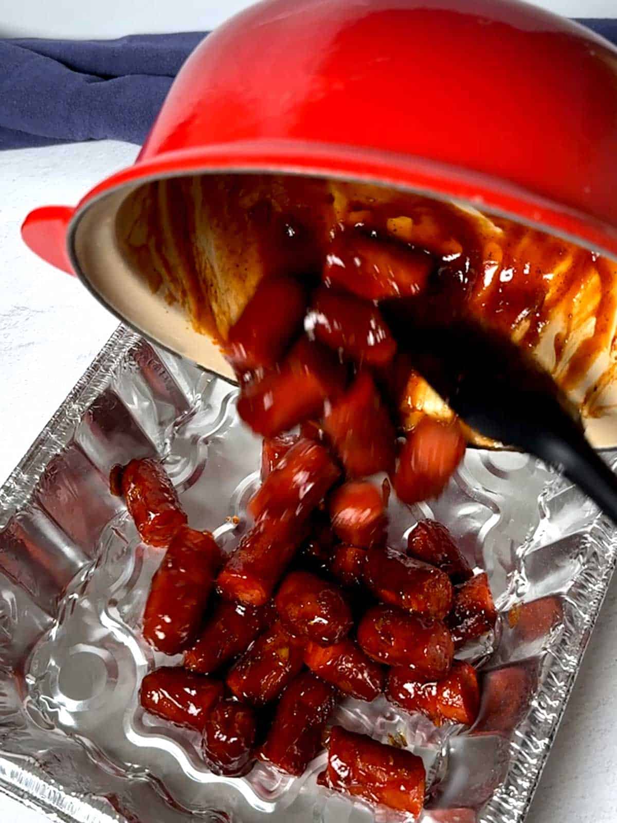 Transferring the hot dogs to a disposable aluminum pan.