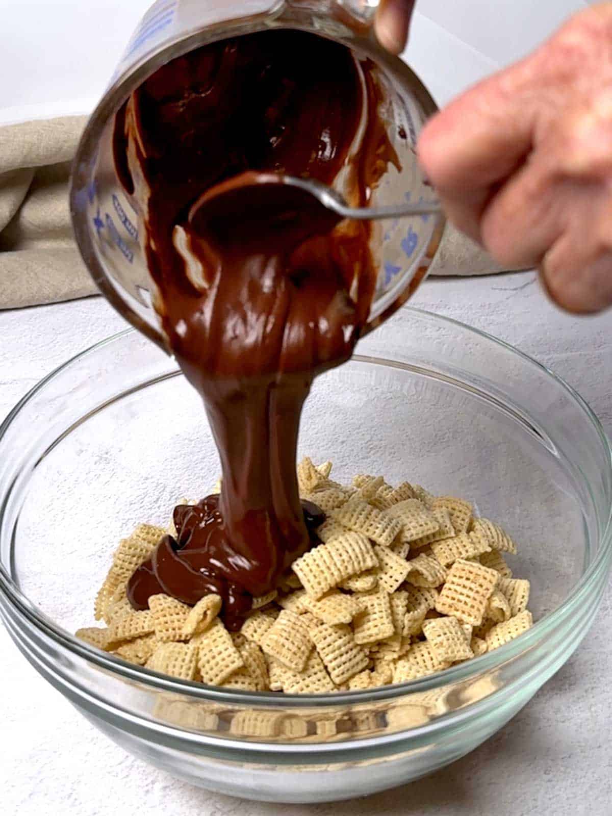 Adding chocolate mixture to the Chex cereal.