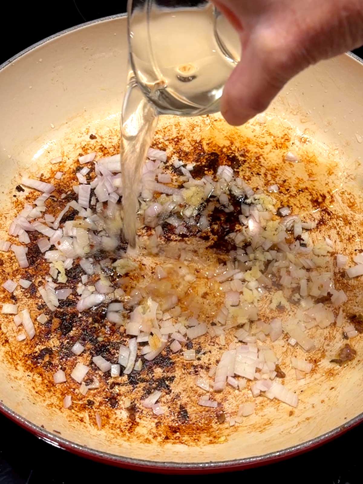 Adding wine to deglaze the pan.