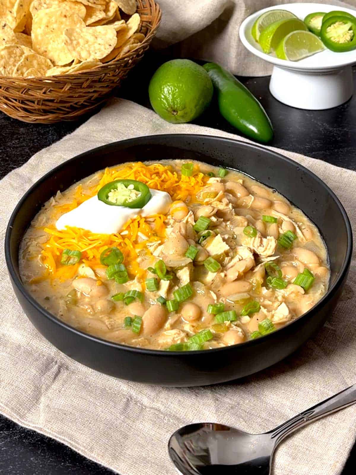 White chicken chili with cheese, sour cream, and a jalapeño slice.