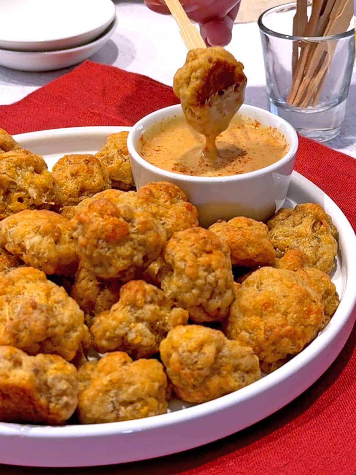 Dipping sausage ball into maple Dijon dipping sauce.
