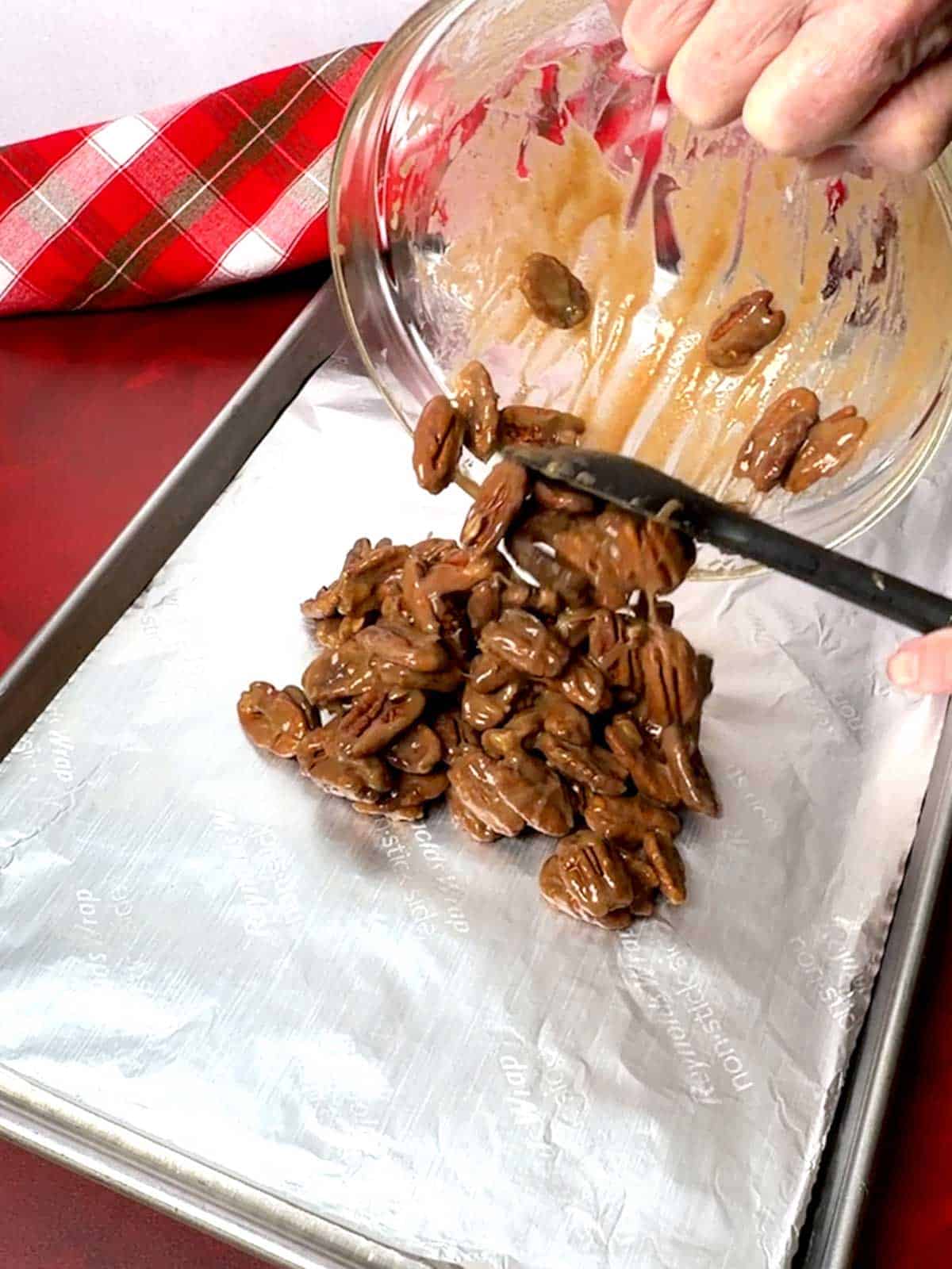 Transferring coated pecans to prepared baking sheet.