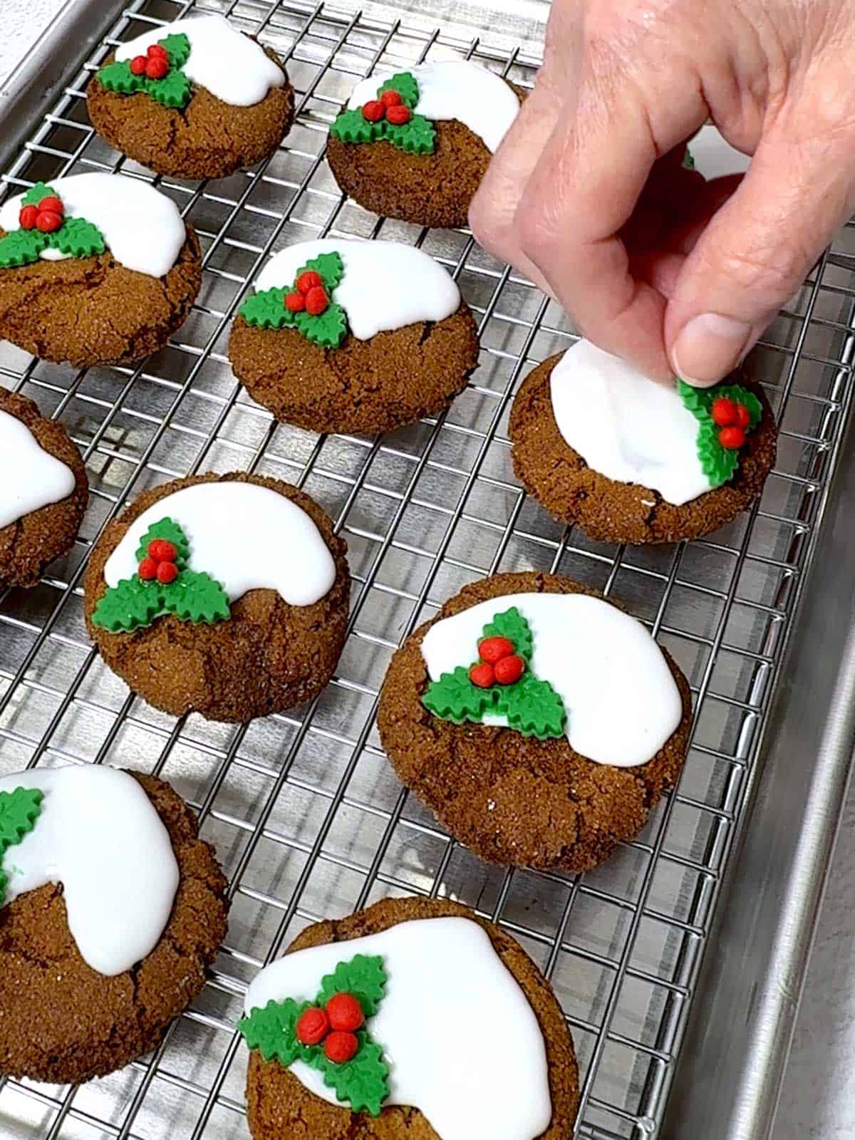 Placing holly leaves with berries on decorated oookies.