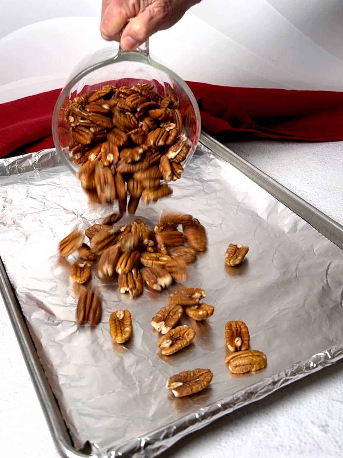 Adding pecans to prepared baking sheet.