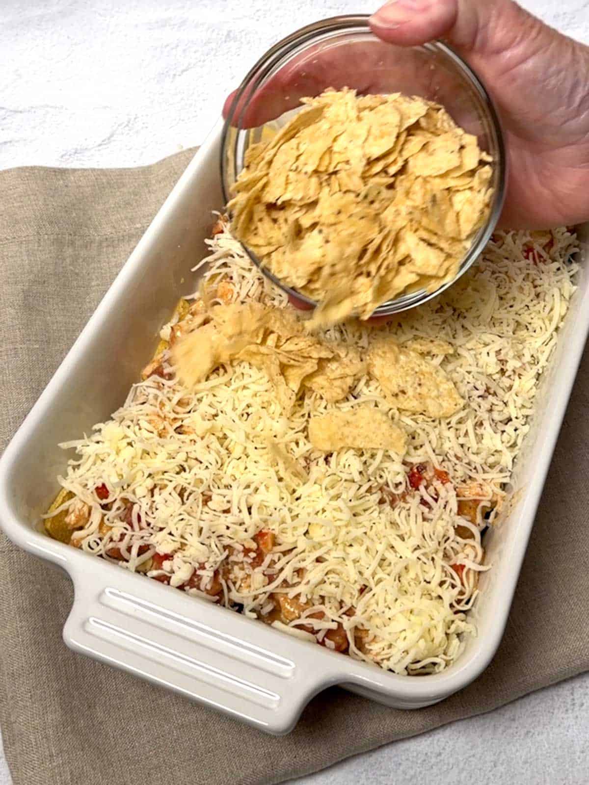 Adding crushed tortilla chips to the casserole.