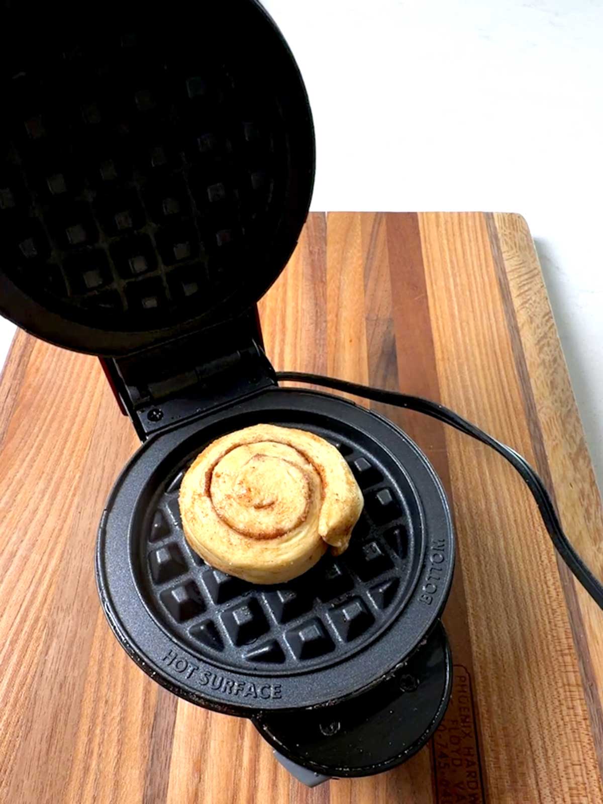 Cinnamon roll placed on the bottom plate of the Dash mini waffle maker.