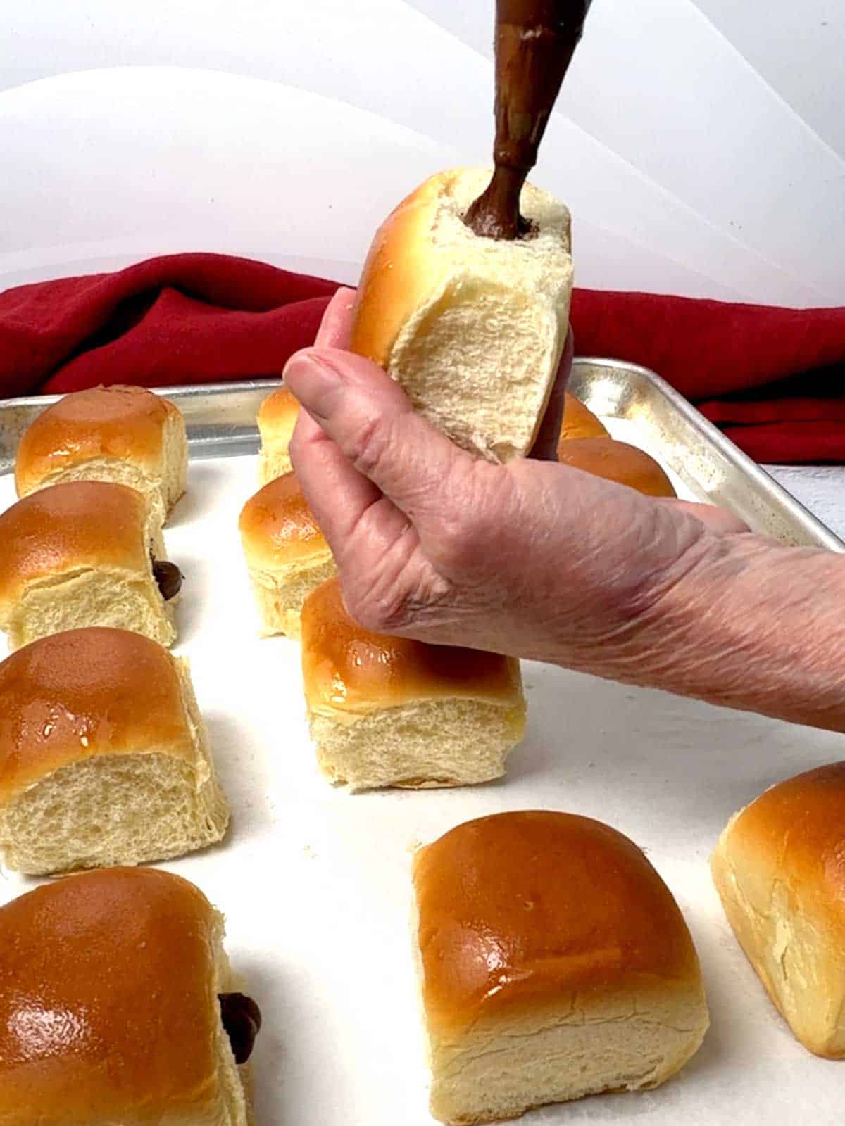 Piping the whipped ganache into the pocket of the King's Hawaiian Roll.