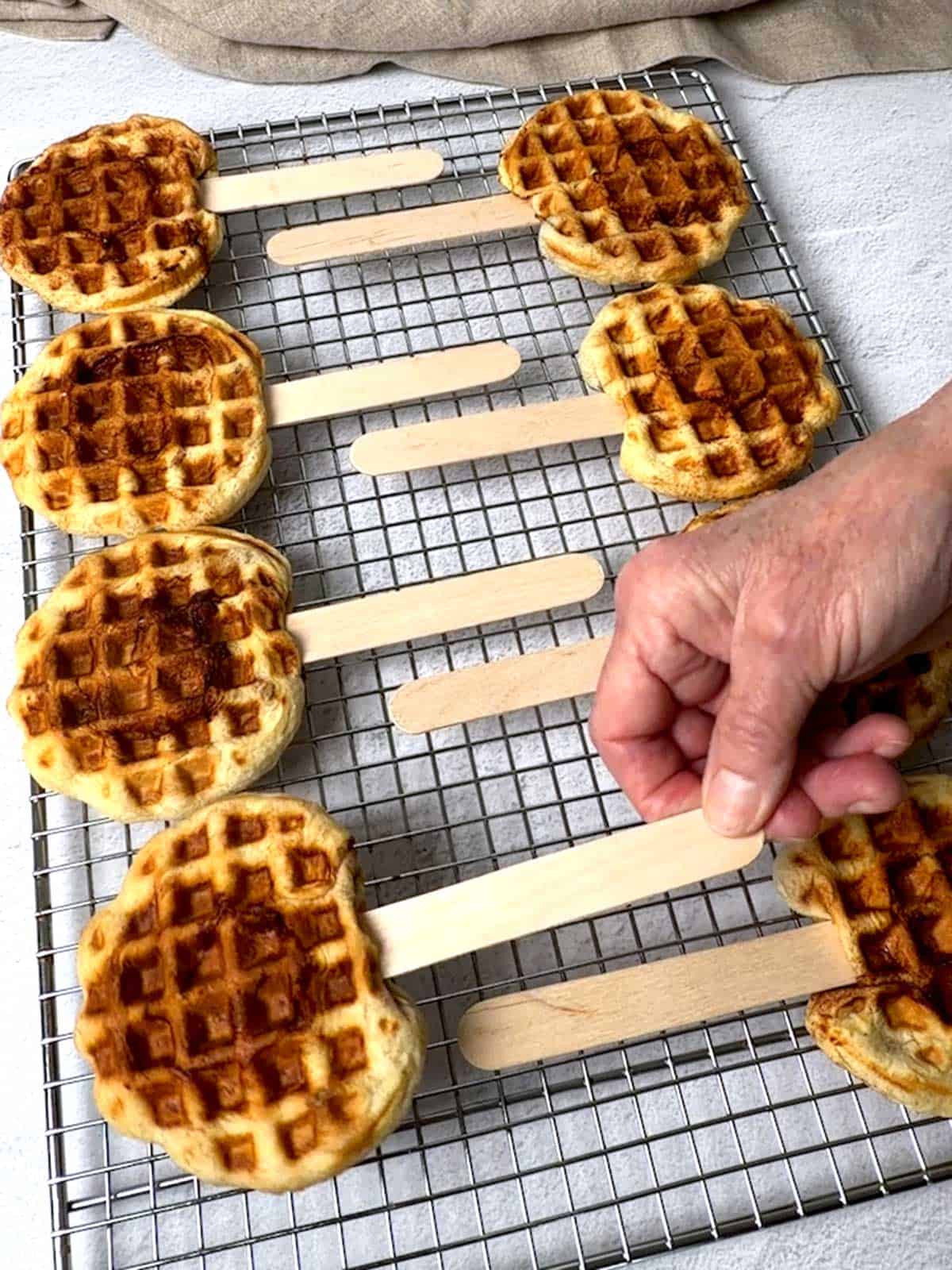 Placing the cooked cinnamon roll waffle on a wire rack to cool.