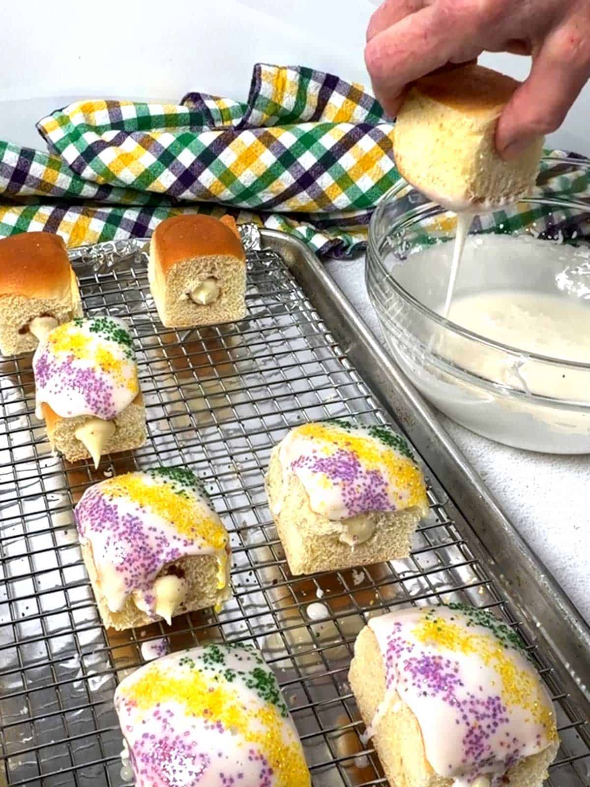 Dipping a filled Hawaiian roll in icing.
