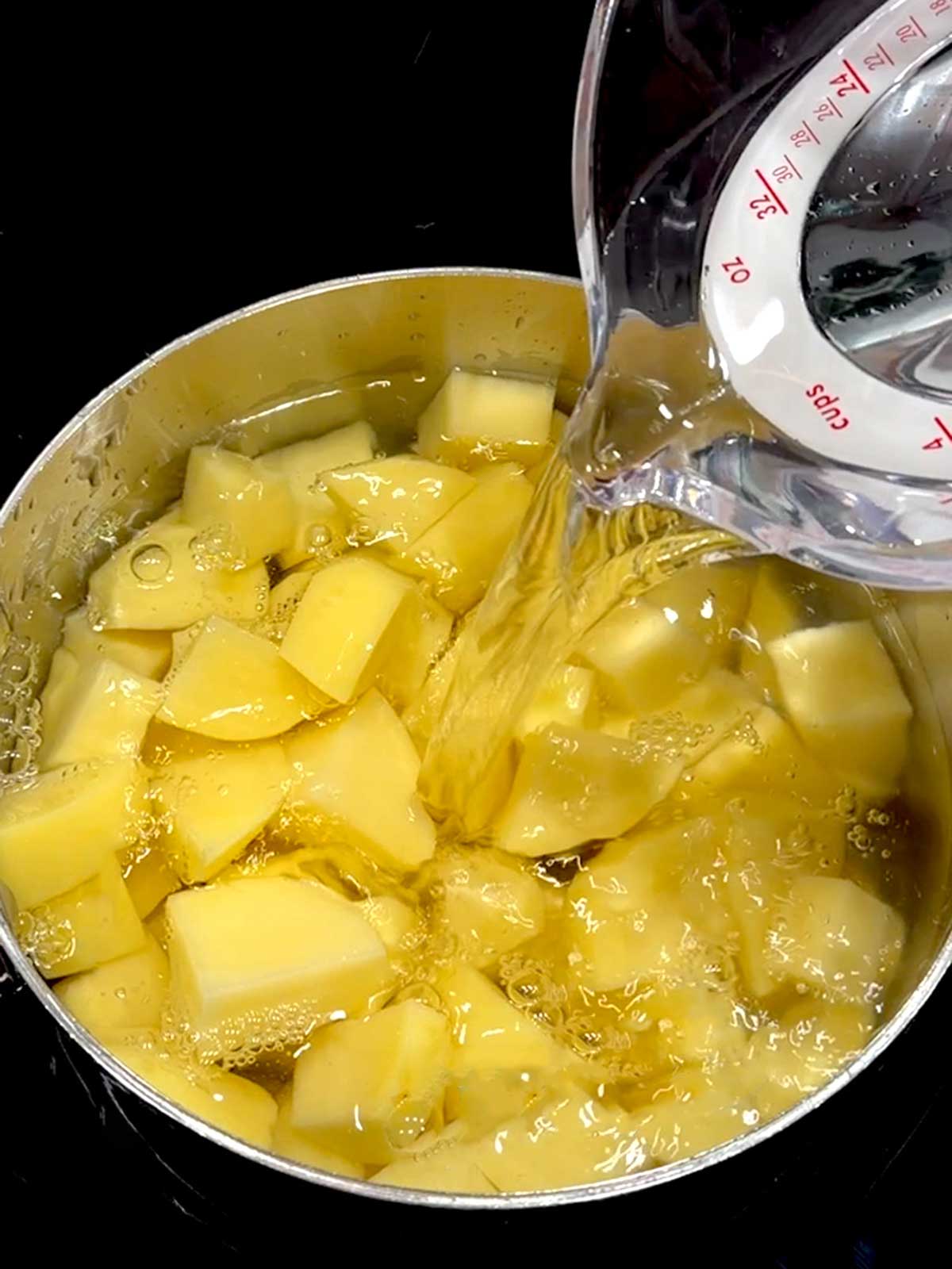 Adding water to the saucepan with the potatoes.