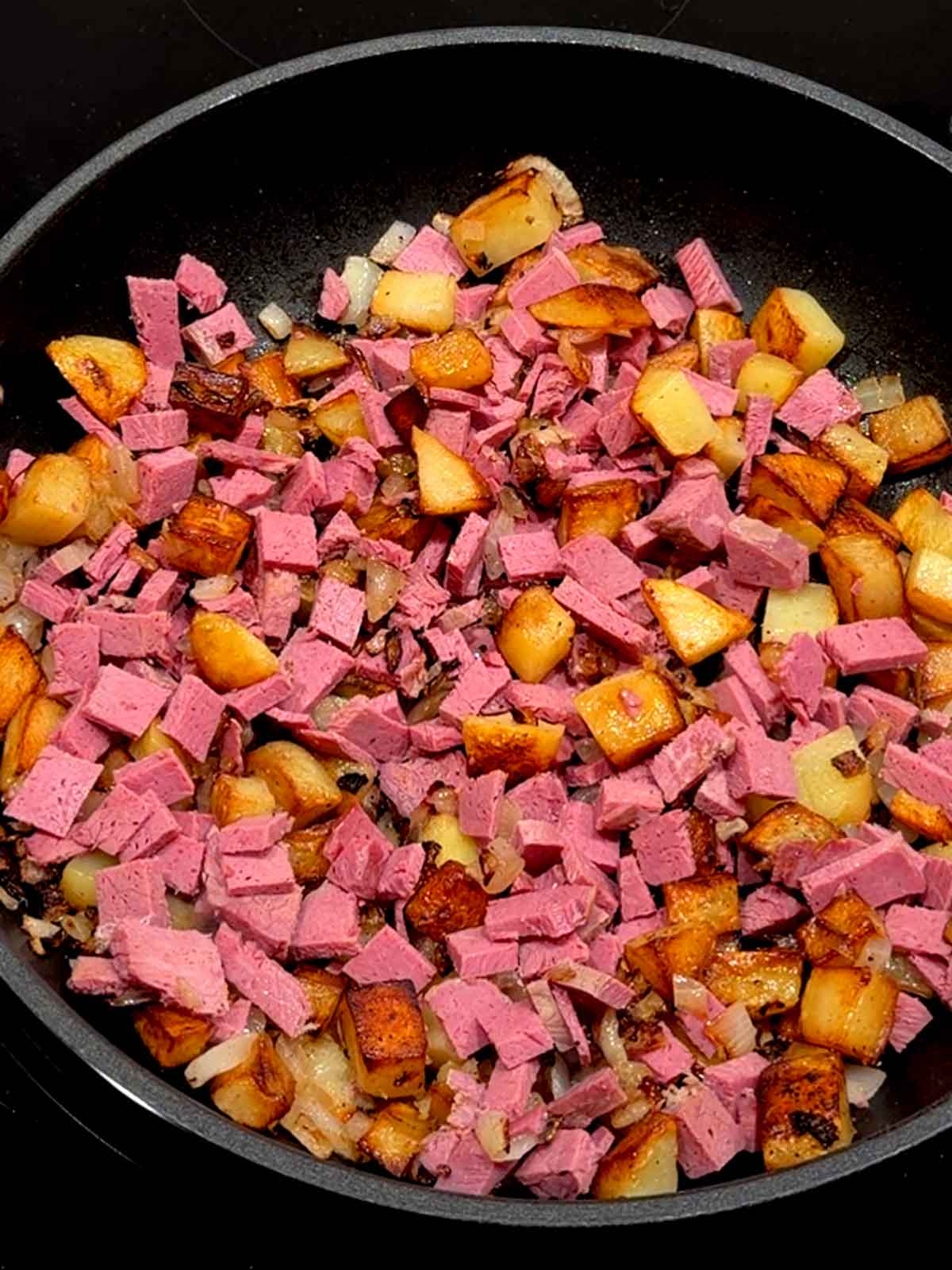 Corned beef added to the potatoes and onions.