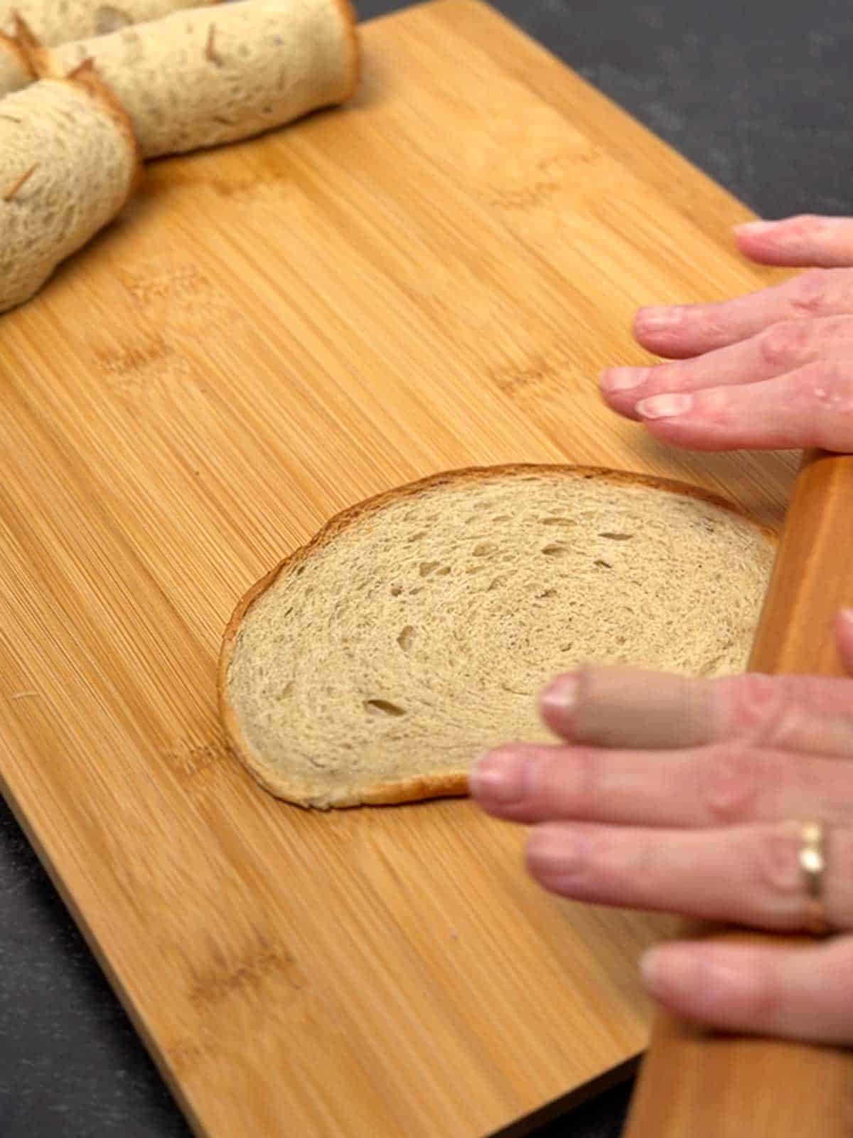 Flattening a piece of rye bread with a rolling pin.