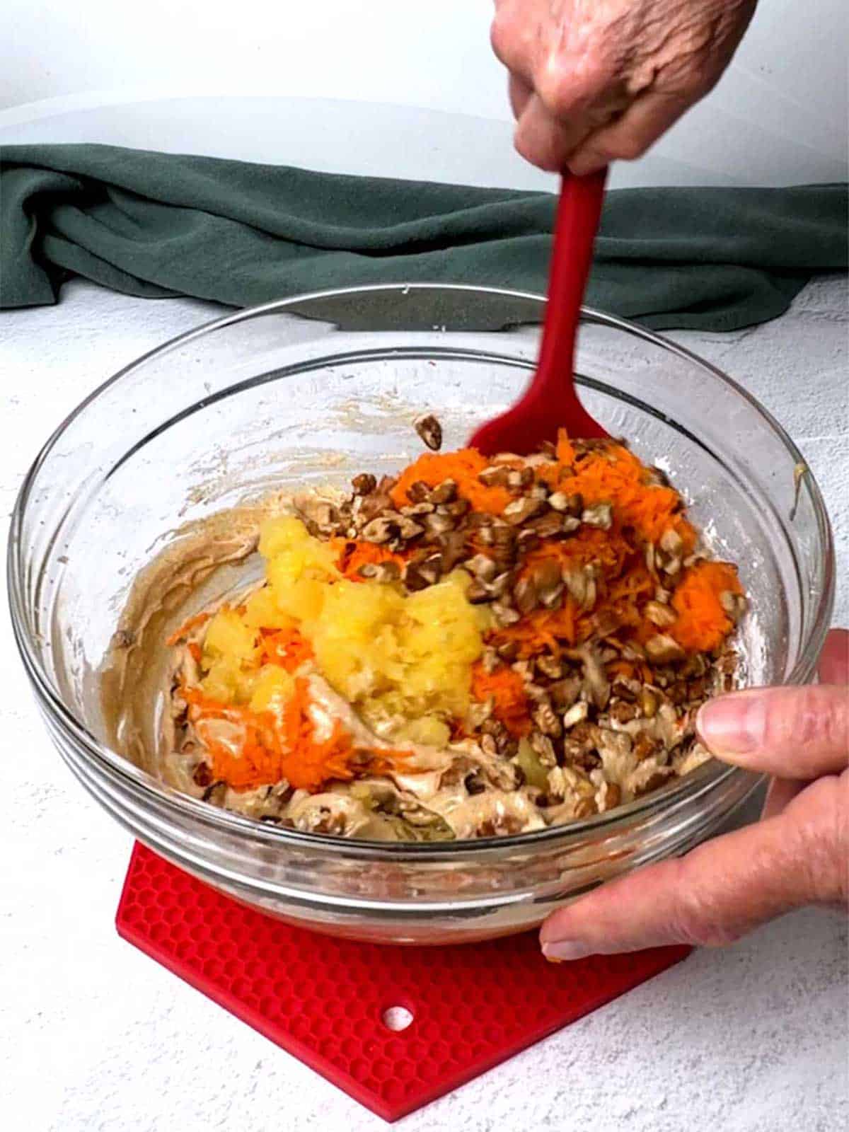 Folding in the carrots, pineapple, and pecans to the batter.