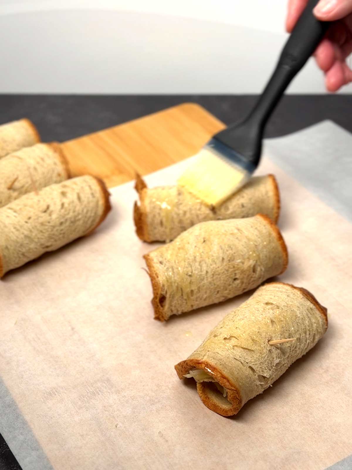 Brushing the outside of the Reuben rollups with melted butter.