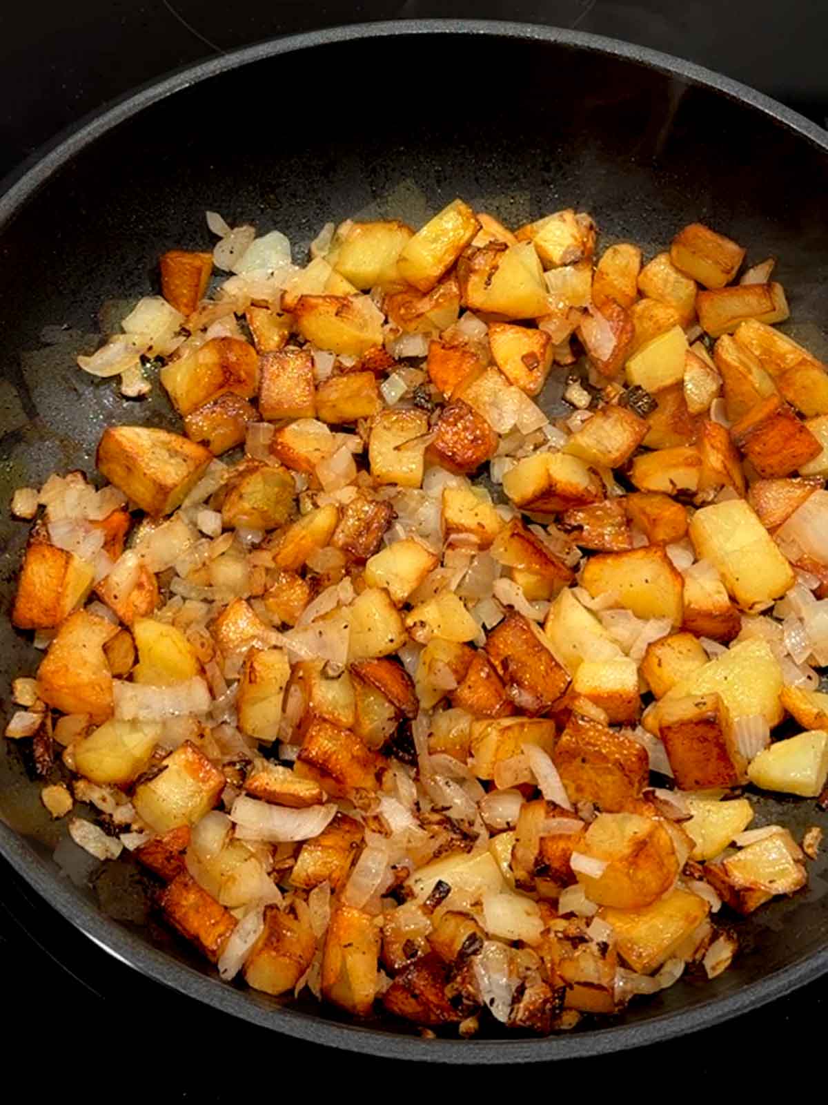 Onions cooked with potatoes in a skillet.