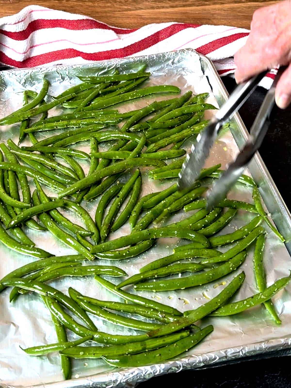 Spreading the green beans on the hot baking sheet.