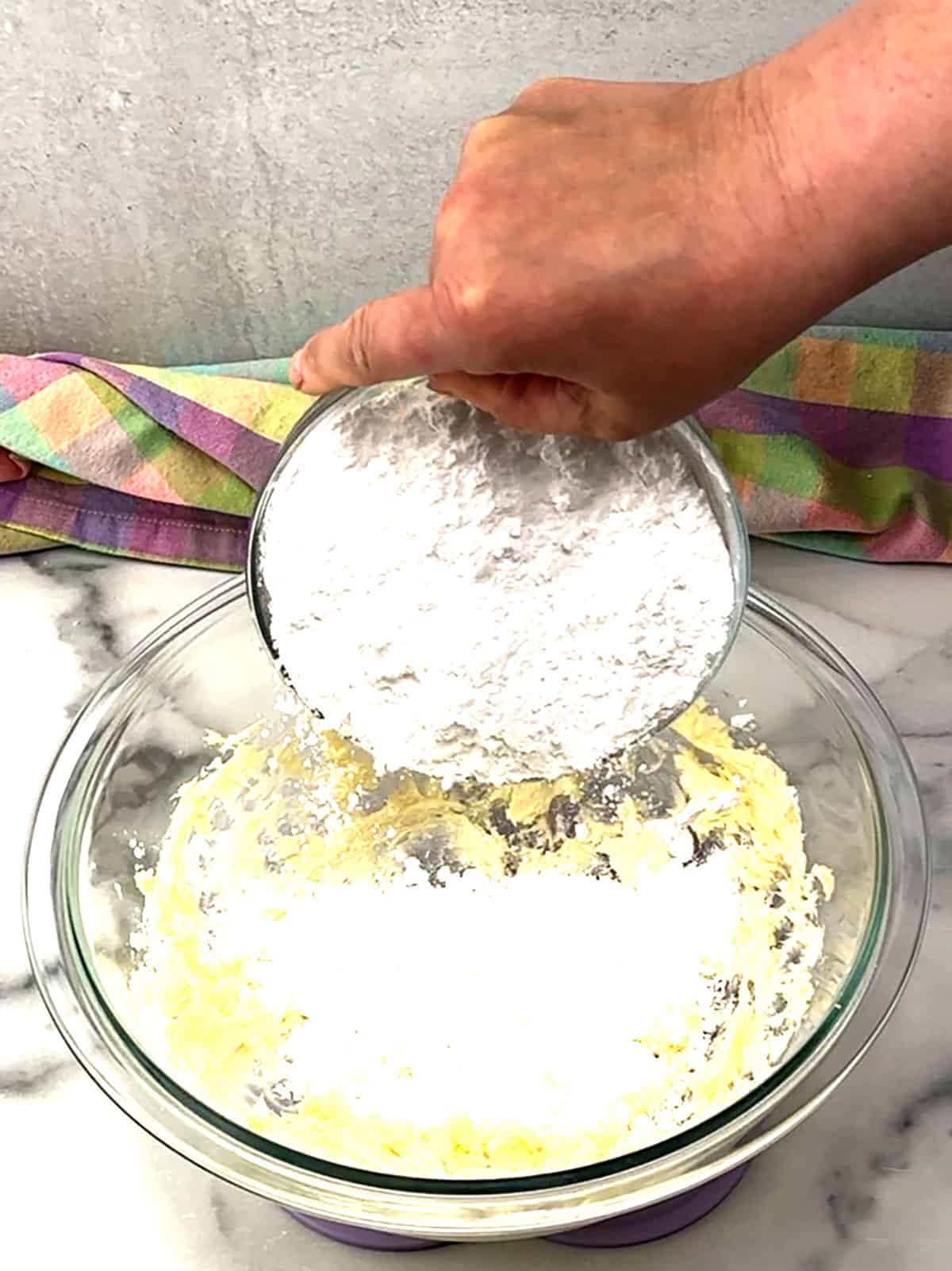 adding powdered sugar to butter for frosting