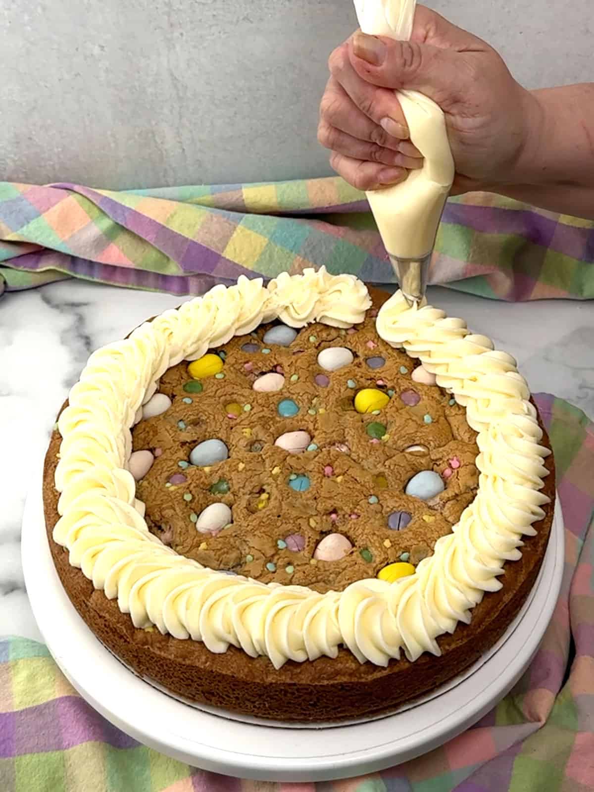 piping frosting around the edge of the cookie cake