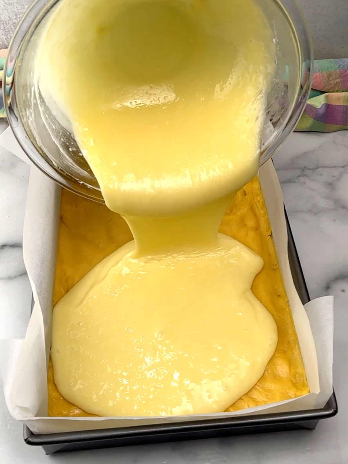 pouring cream cheese mixture on top of cake mixture