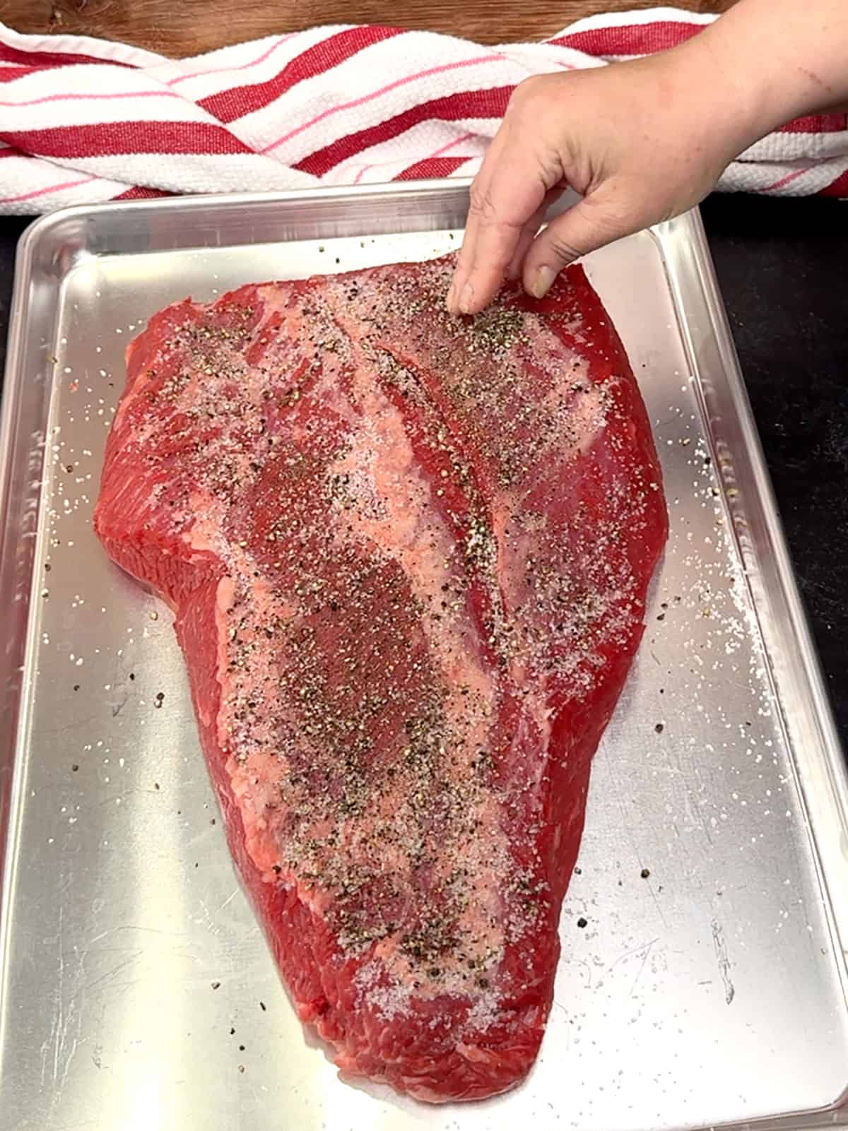 sprinkling salt and pepper on brisket
